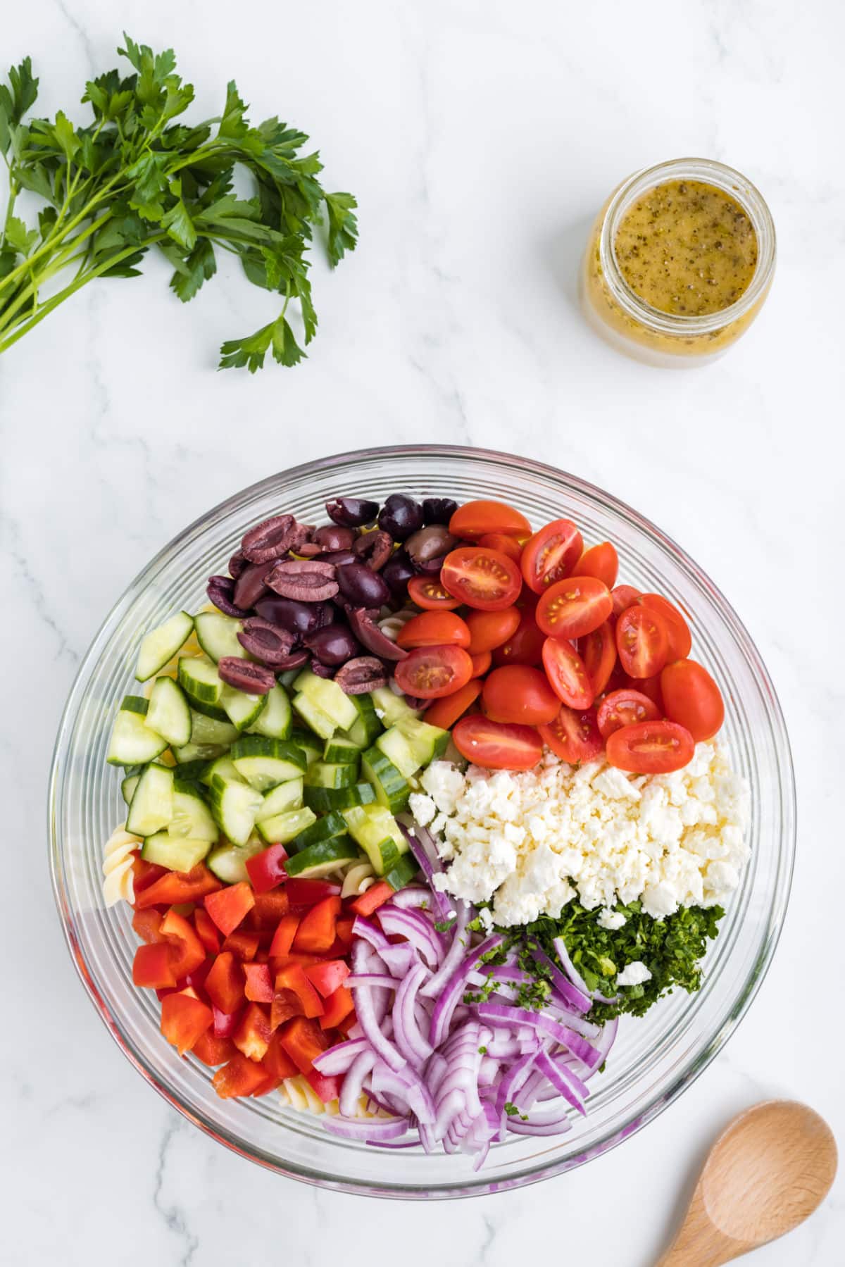 Chopped vegetables and pasta in a glass mixing bowl. 