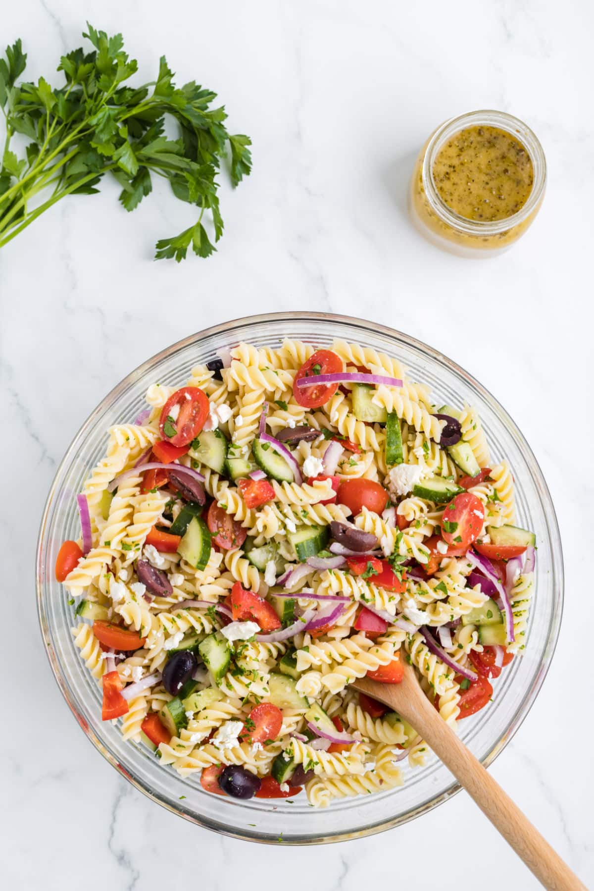 A bowl of Greek pasta salad next to Italian parsley. 