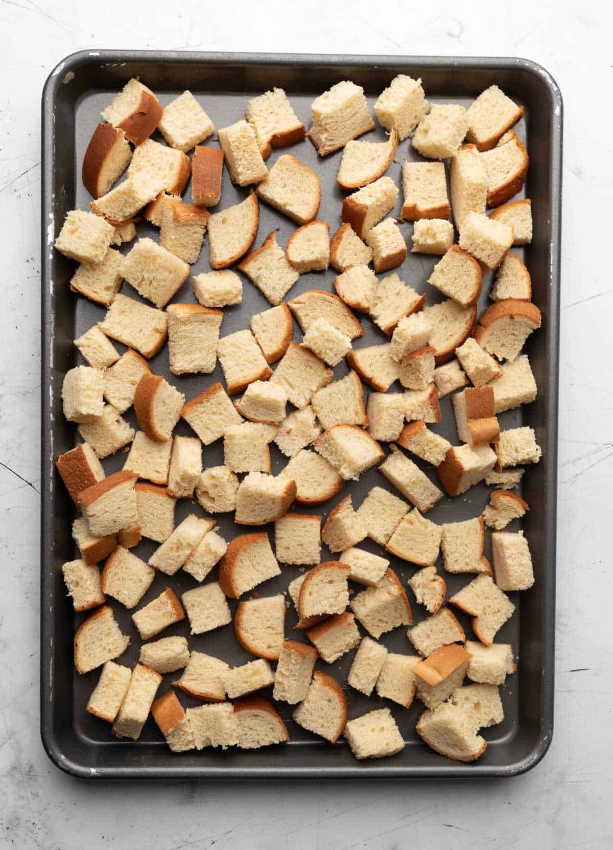 Toasted bread cubes on a rimmed baking pan.