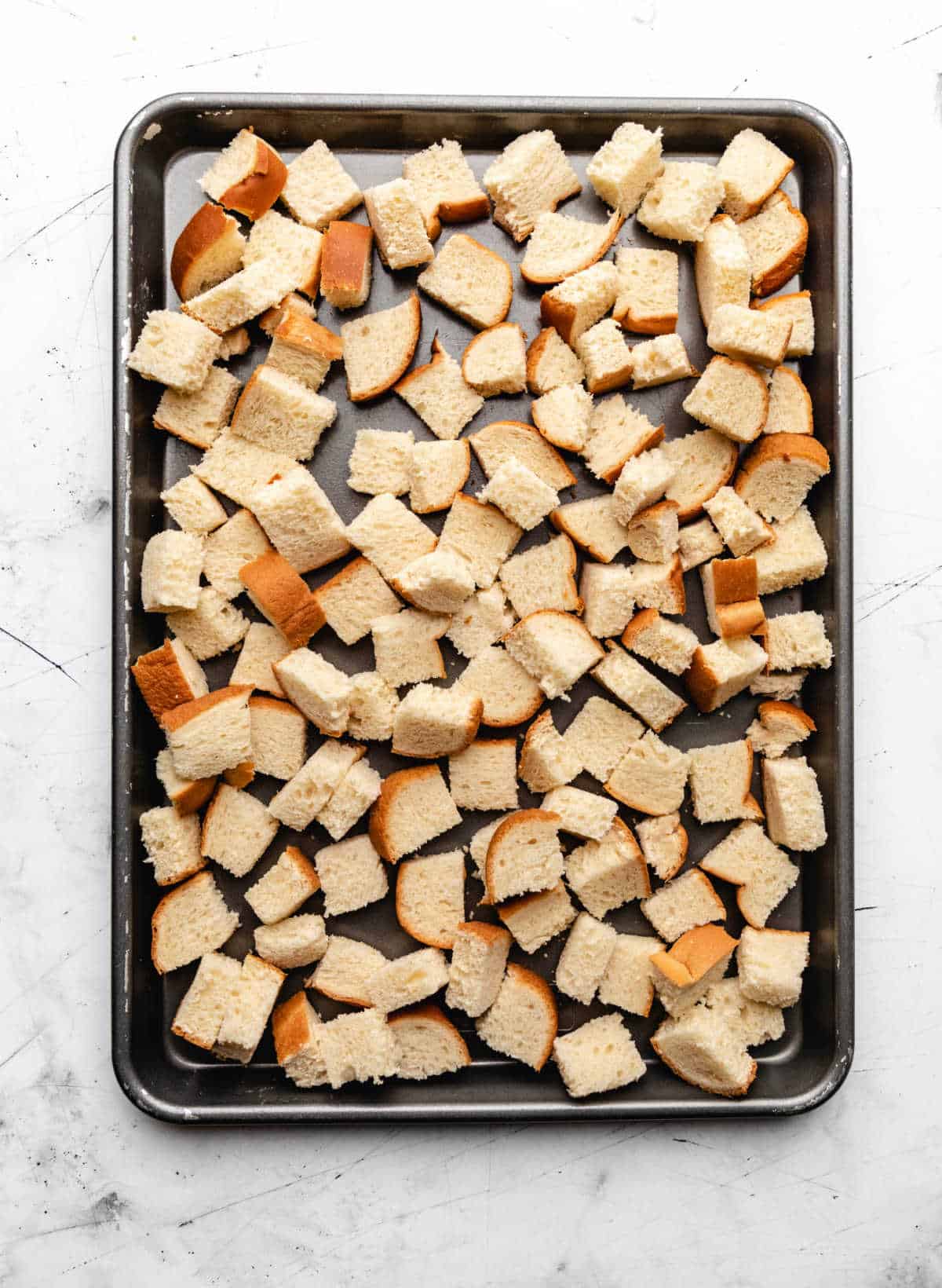 Bread cubes on a rimmed baking sheet. 