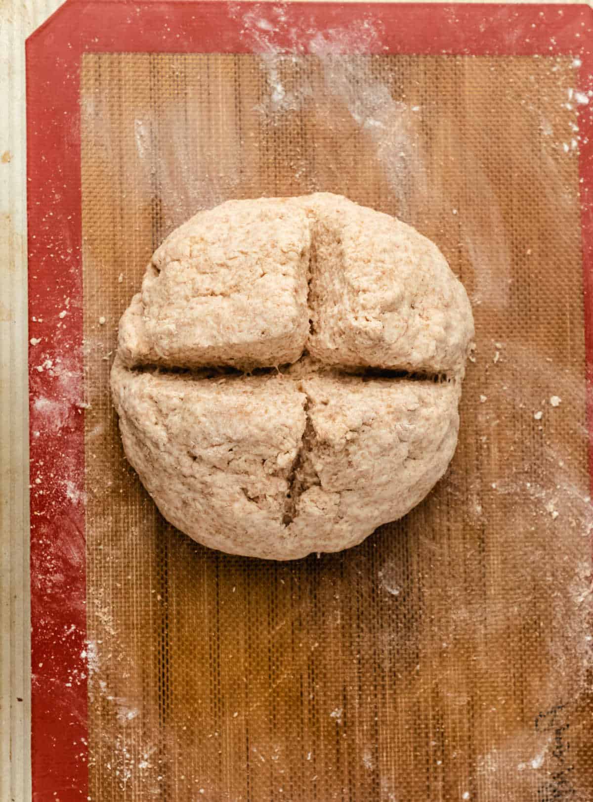 Irish brown soda bread dough with a cross cut into it. 