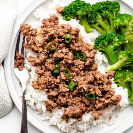 Korean ground beef topped with green onions next to rice and steamed broccoli.