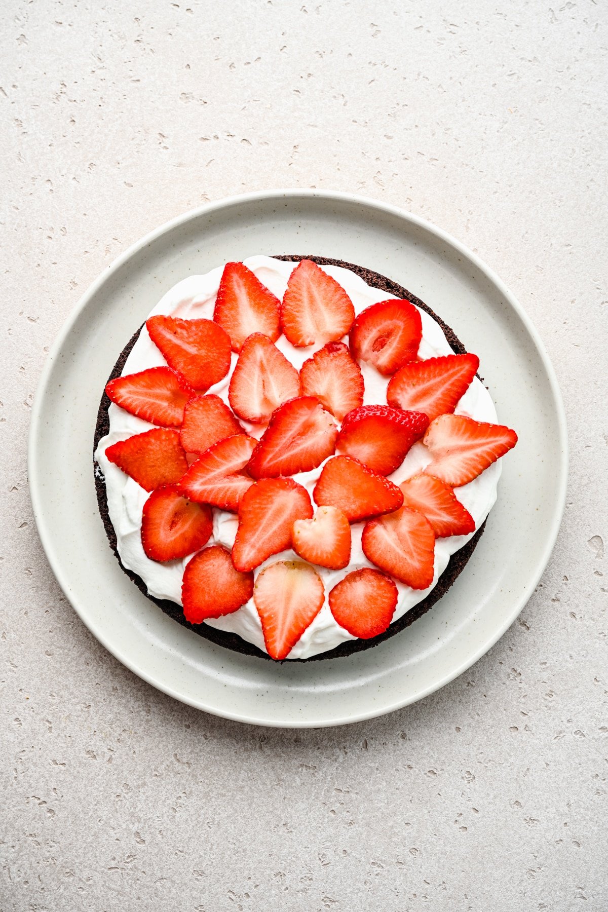 Half of chocolate strawberry cake topped with whipped cream and sliced strawberries. 