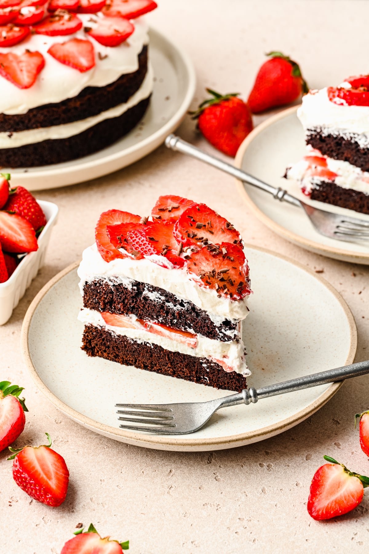 Slice of chocolate strawberry cake on a cream plate with a fork. 