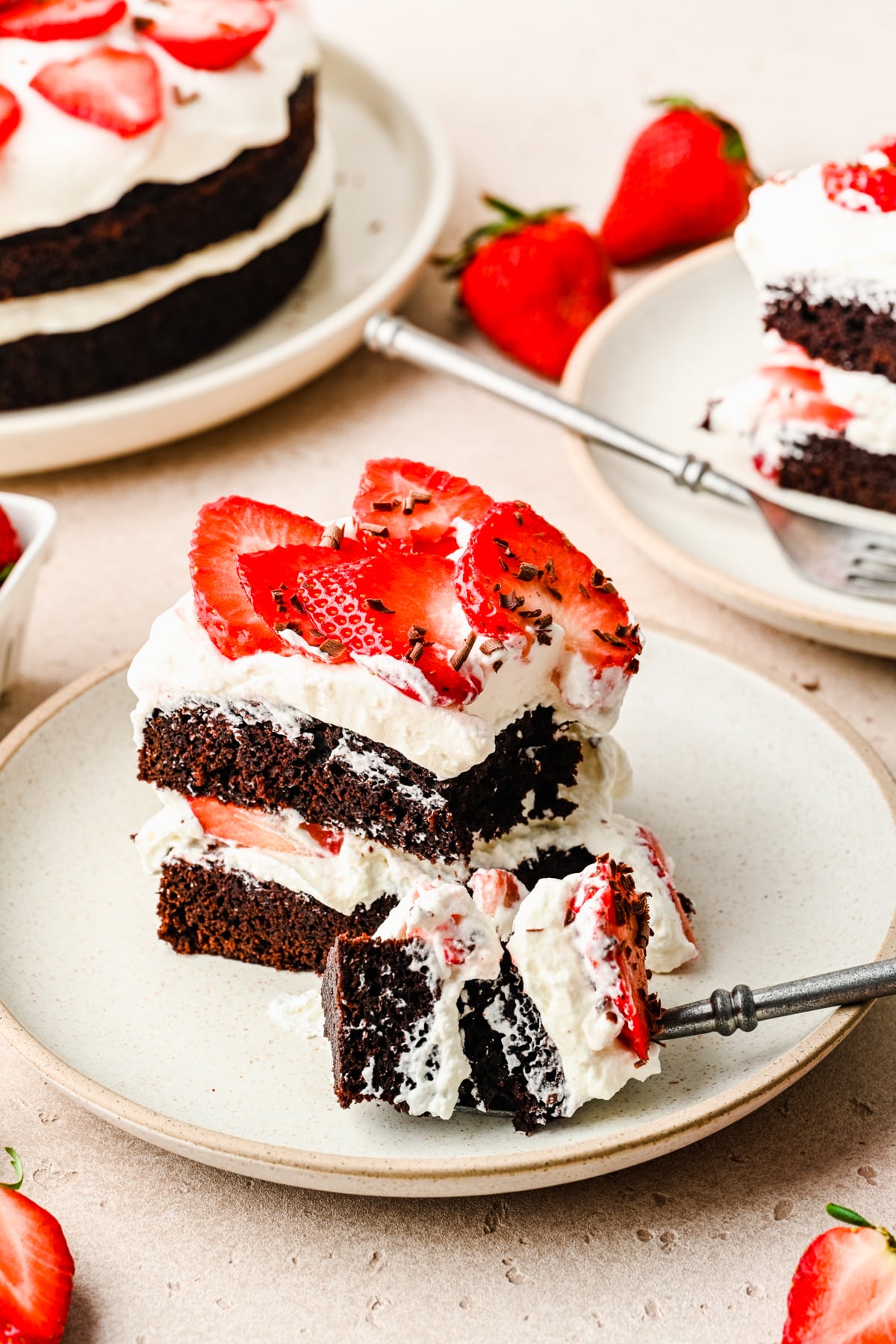 A fork taking a bite of chocolate strawberry cake. 