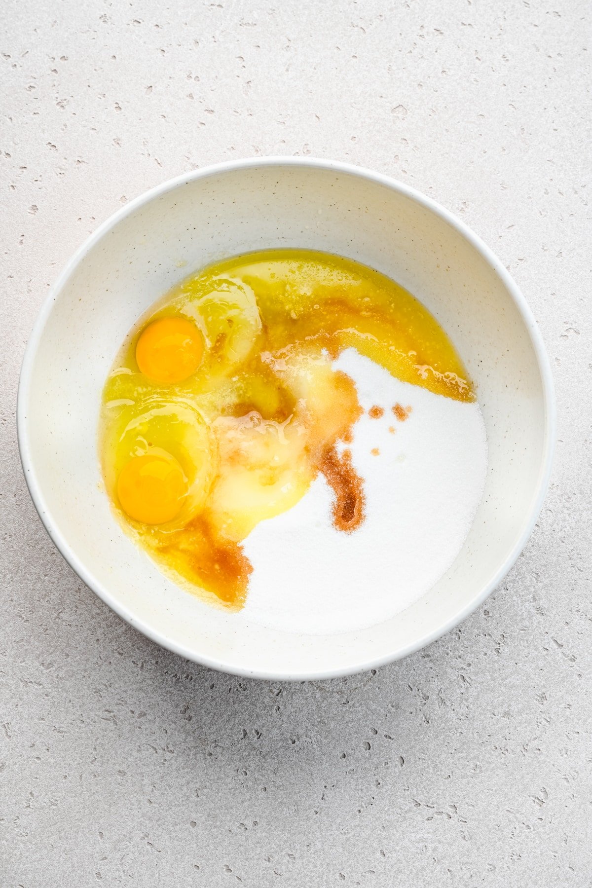 Egg and sugar mixture in a white mixing bowl. 