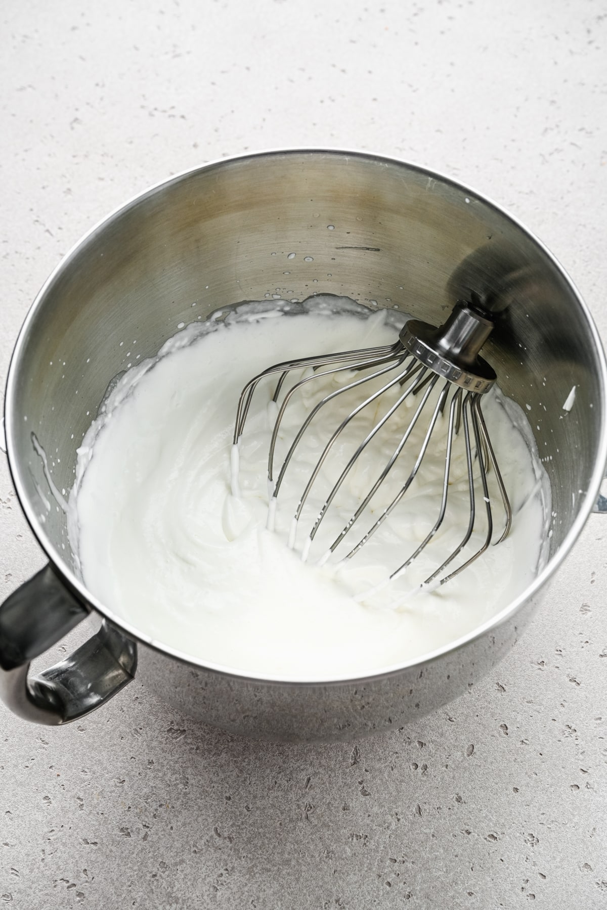 Whipped cream in a silver mixing bowl. 