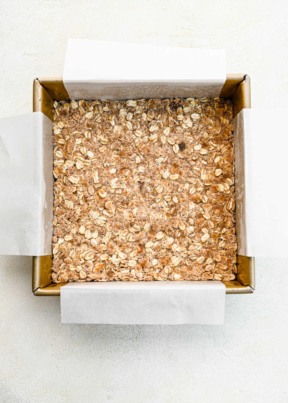 Oatmeal crumble pressed into a baking pan.