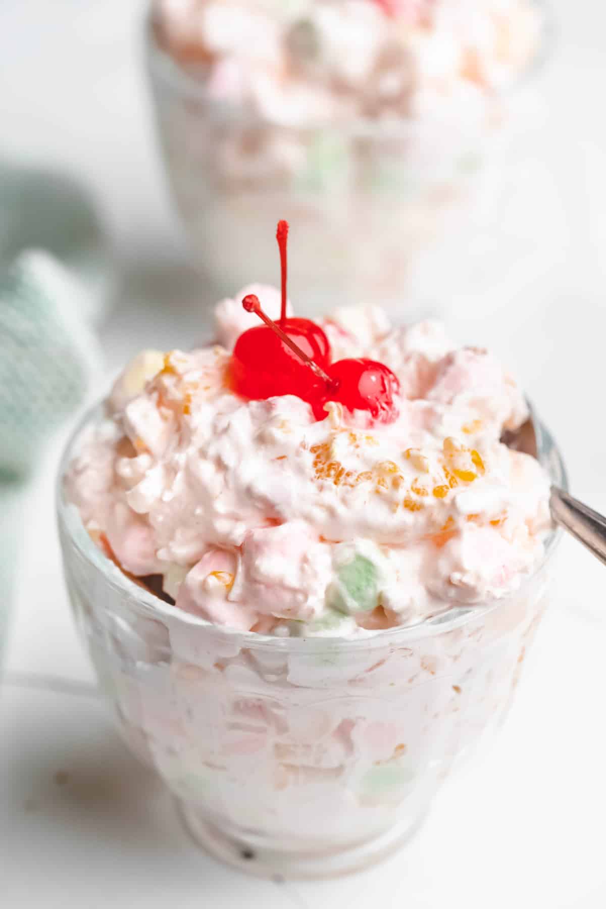 A silver spoon next to a dish of ambrosia salad. 