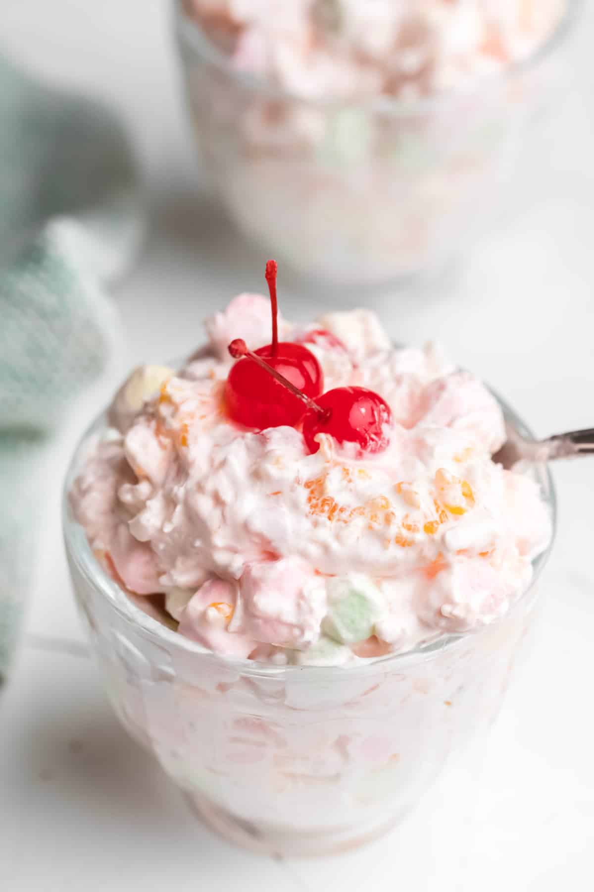 Two dishes of ambrosia salad topped with two cherries. 