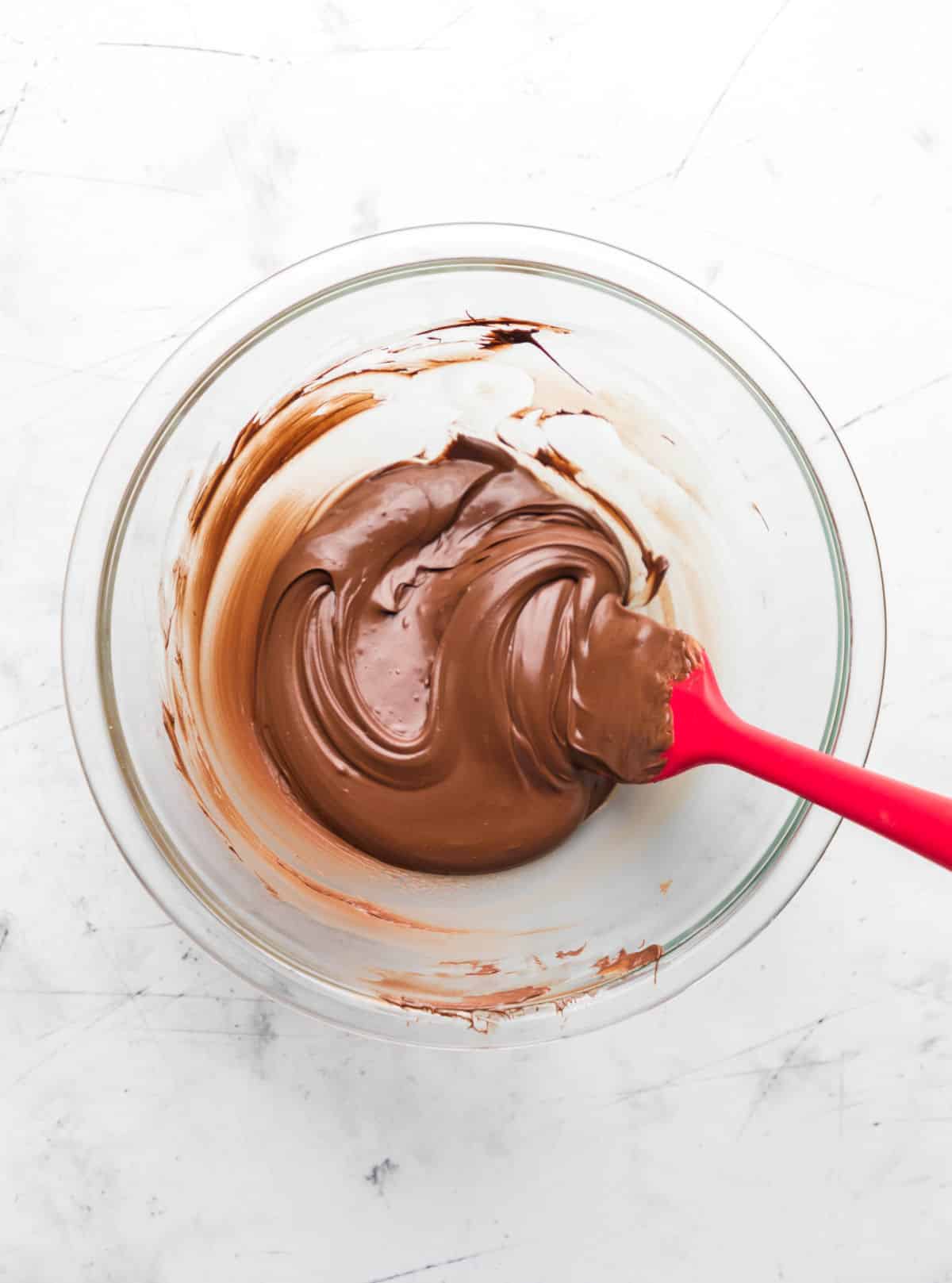 Melted chocolate chips and butterscotch chips in a glass mixing bowl. 