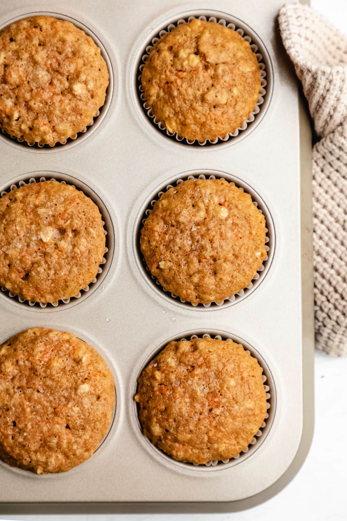 Six carrot oat muffins in a muffin tin. 