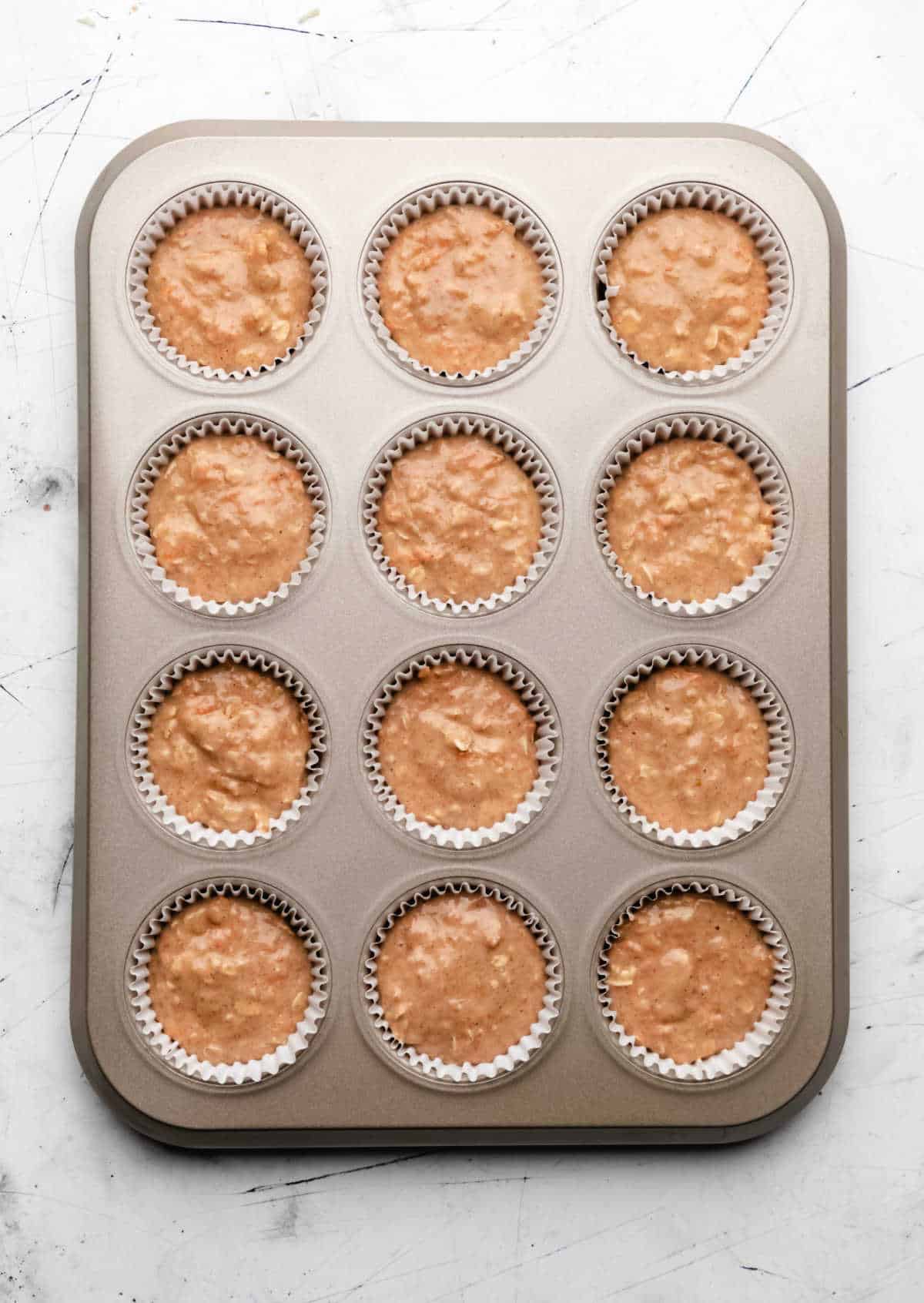 Carrot oat muffin batter in a muffin tin. 