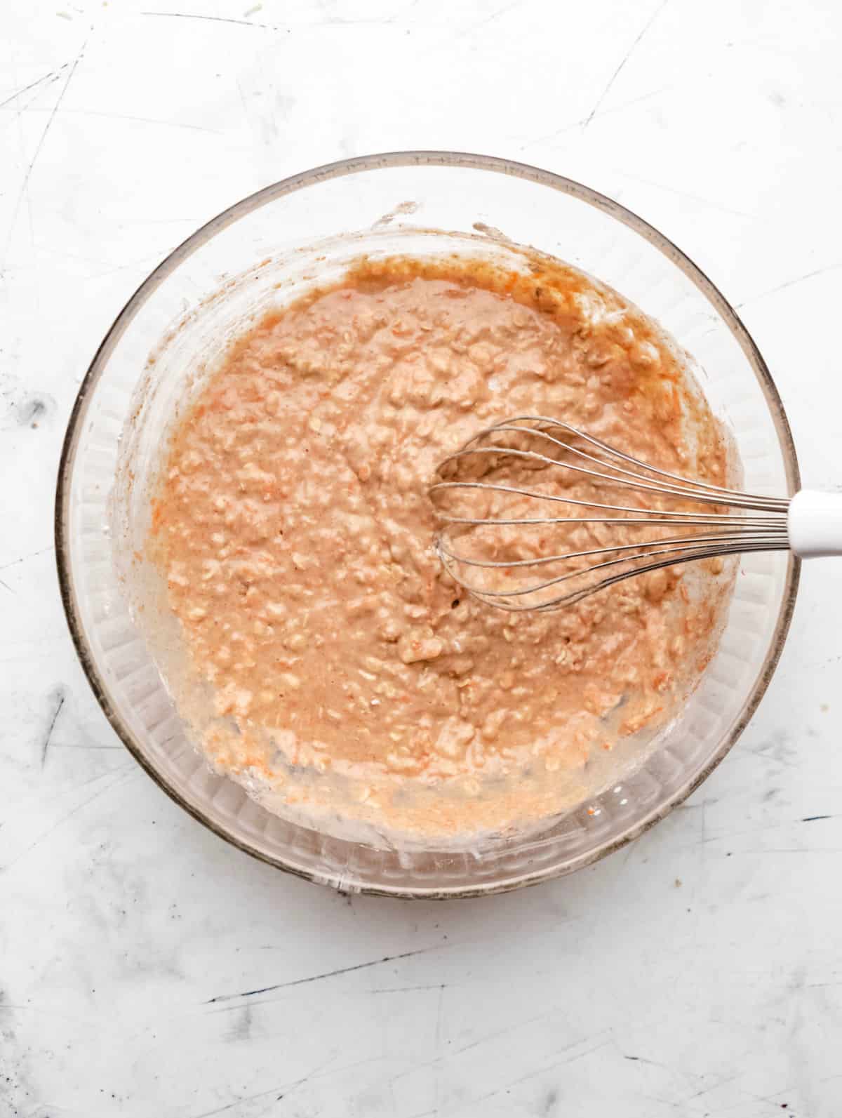 Carrot oat muffin batter in a glass mixing bowl. 