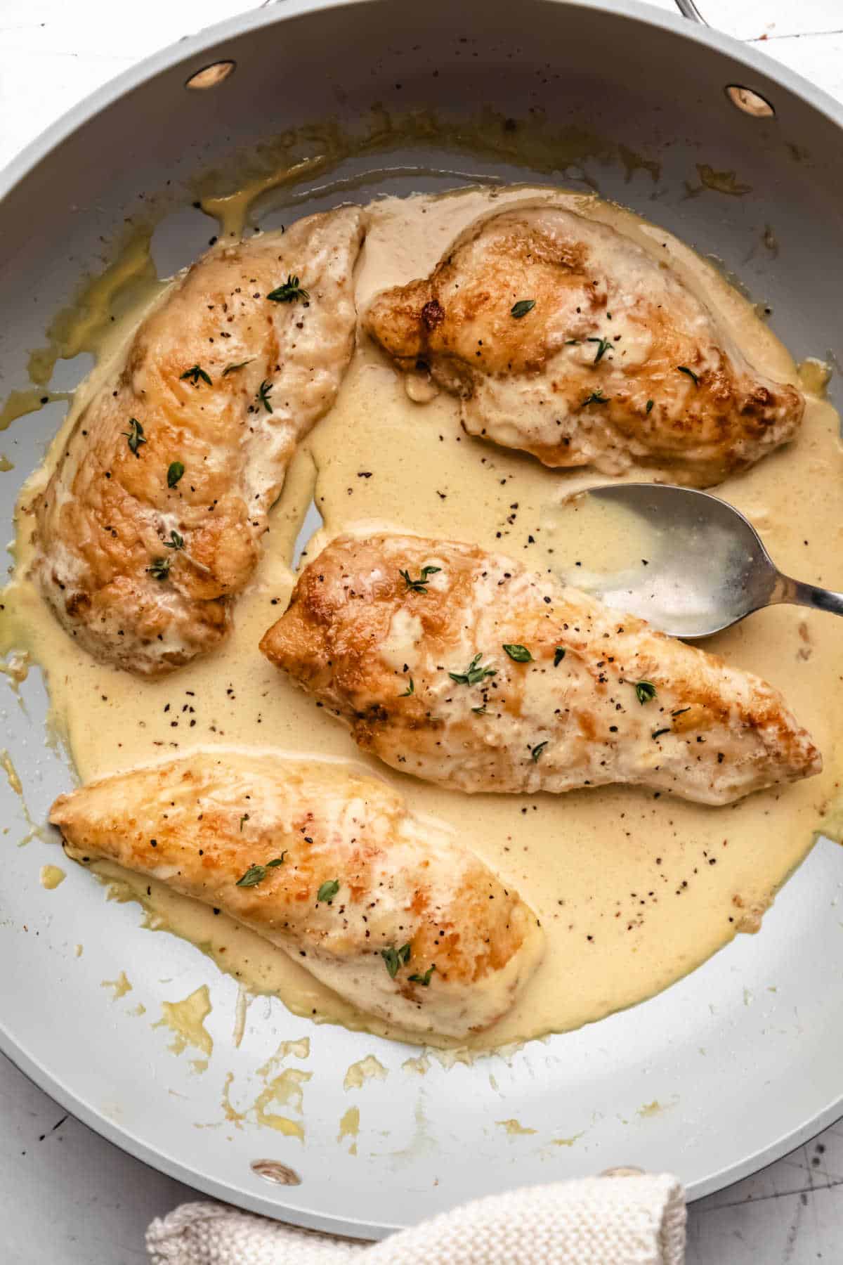 Four cooked chicken breast halves in creamy mustard sauce. 