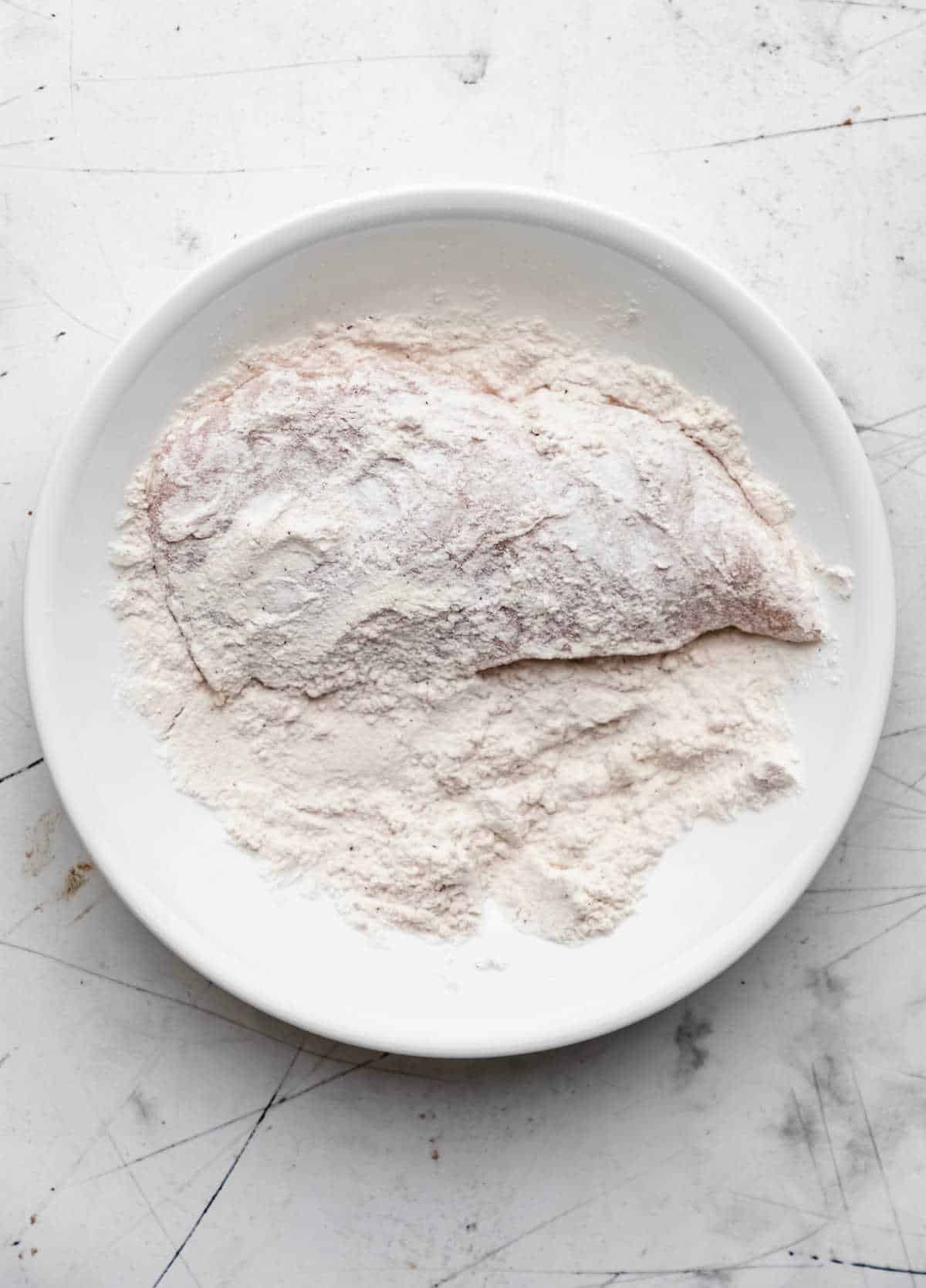 A chicken breast half coated in flour. 
