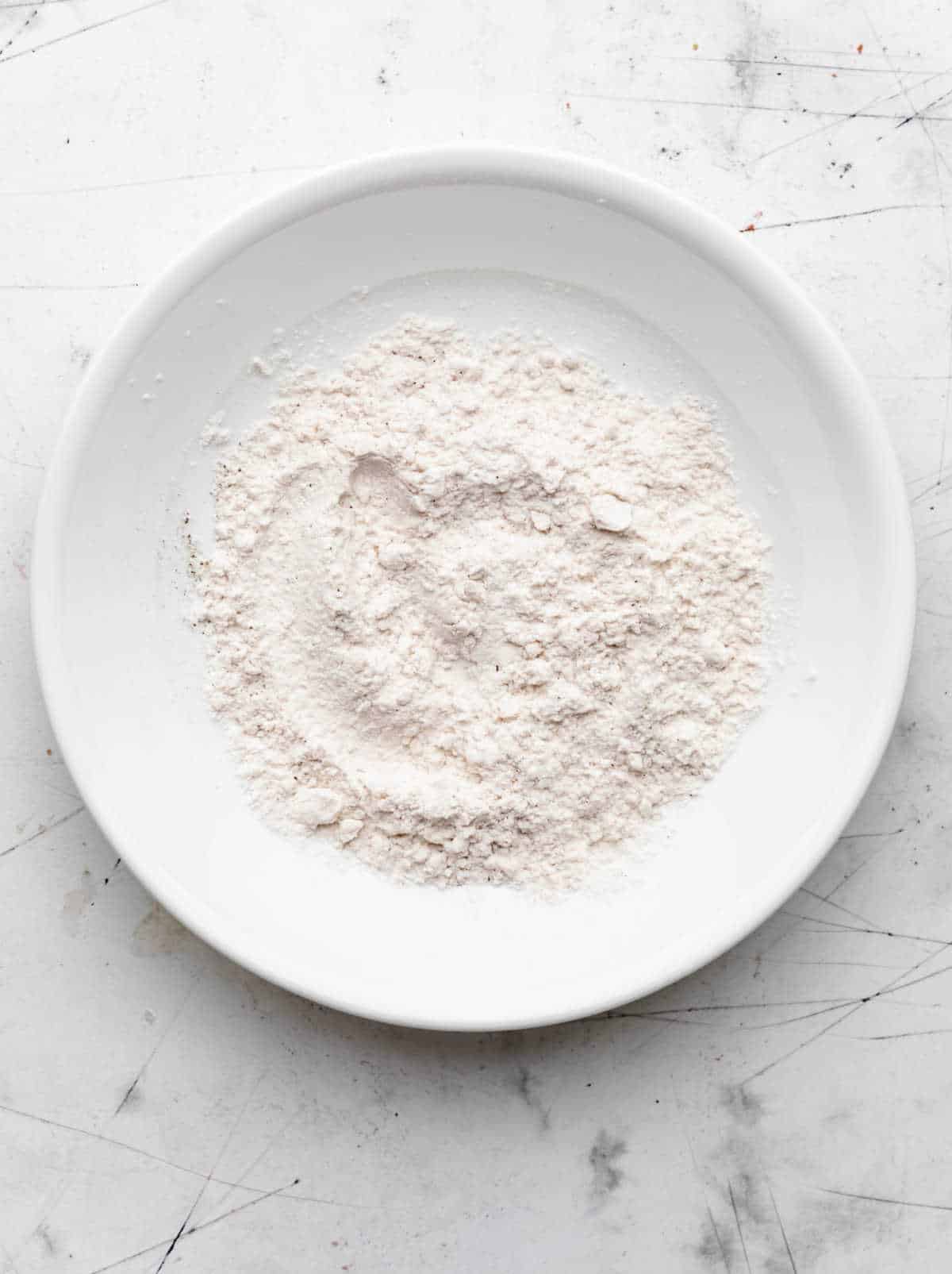Flour  and pepper in a white dish. 
