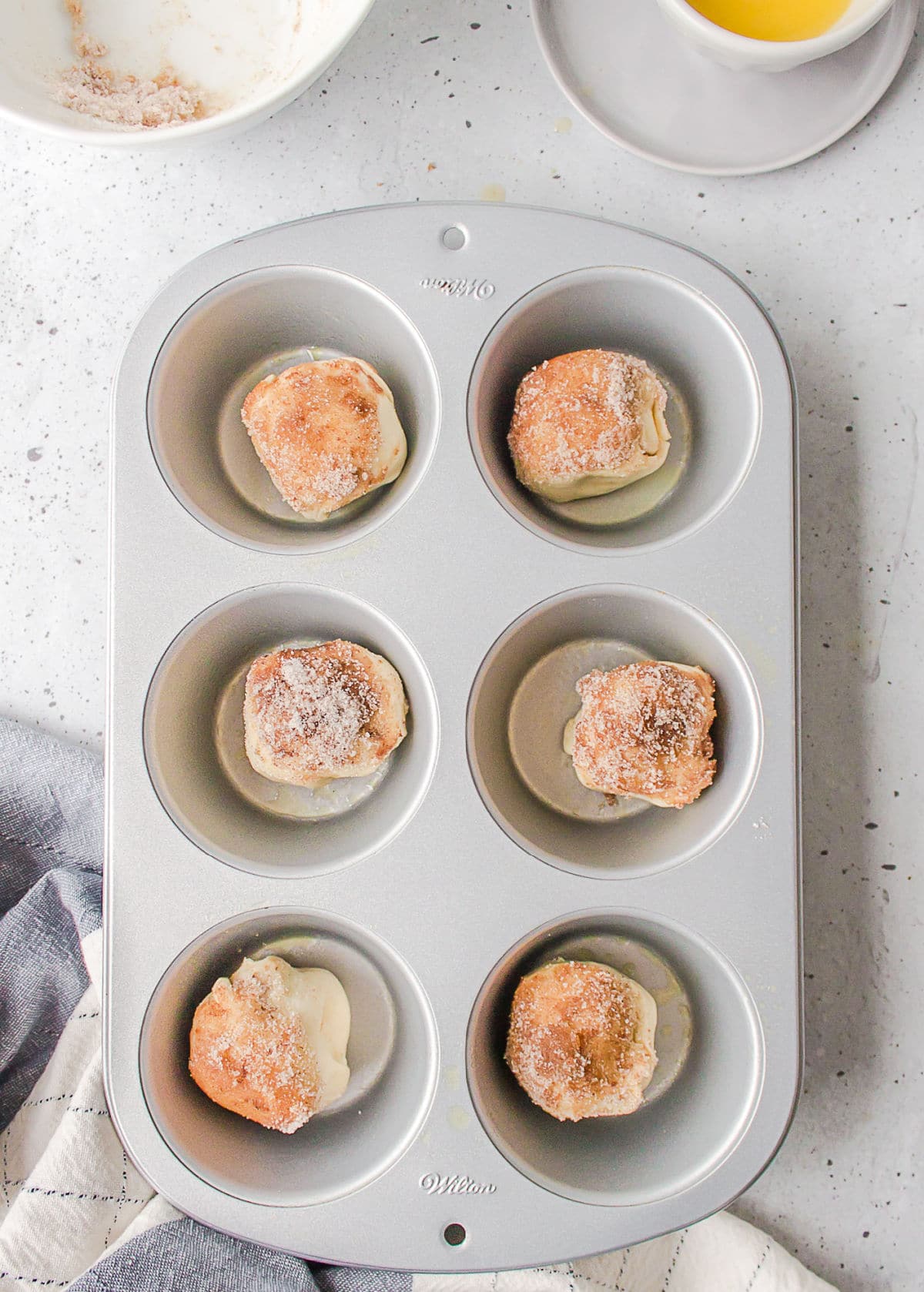 Six unbaked empty tomb rolls in a jumbo muffin tin. 