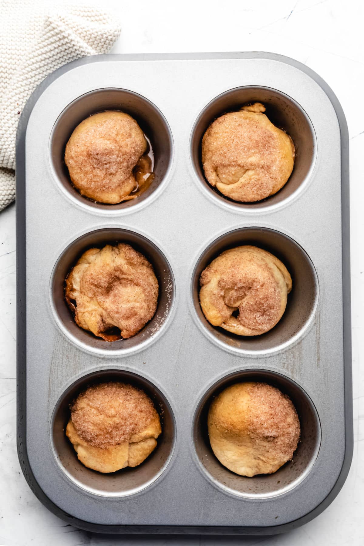 Six empty tomb rolls in a jumbo muffin tin. 