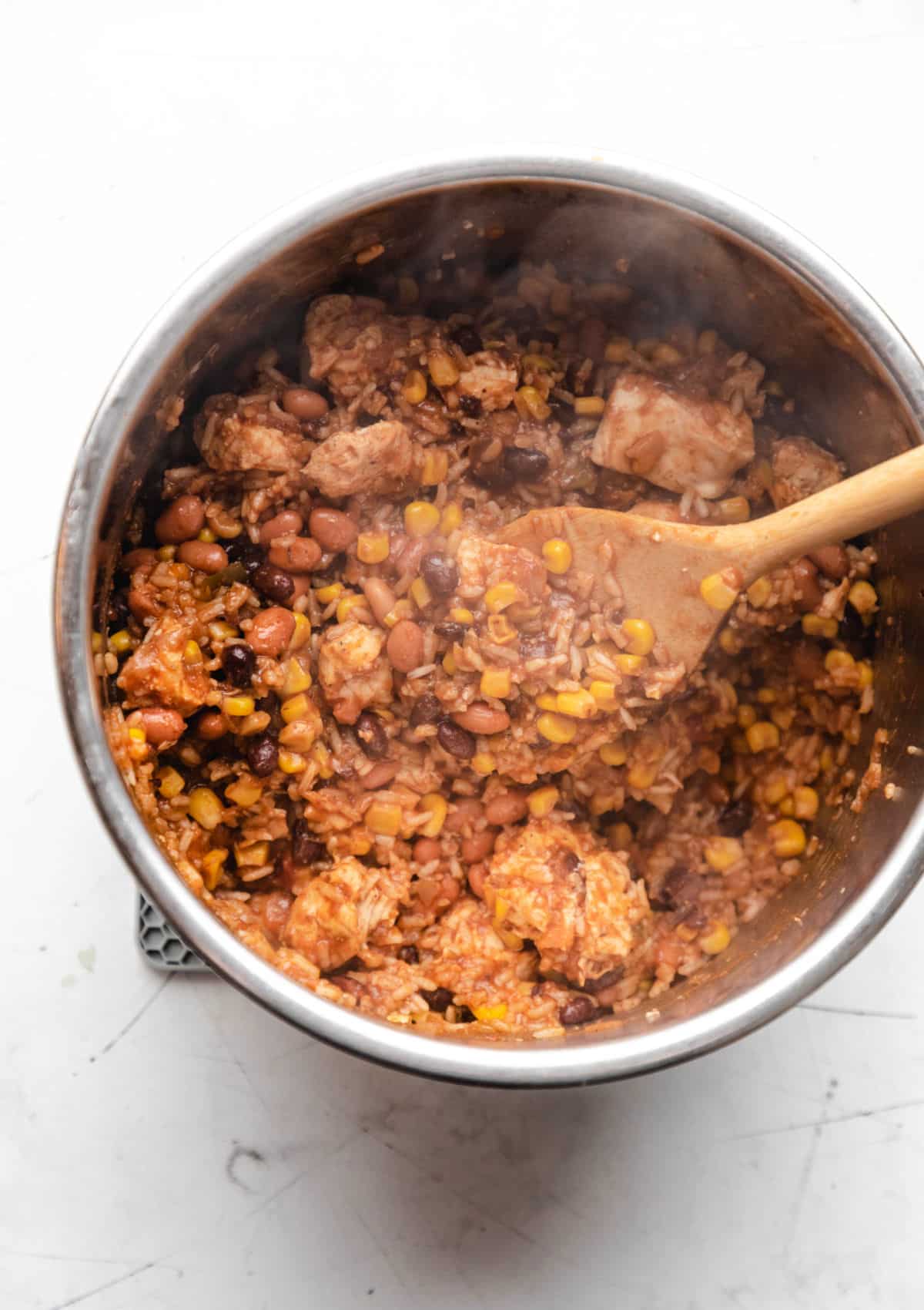 A wooden spoon stirring an instant pot burrito bowl.
