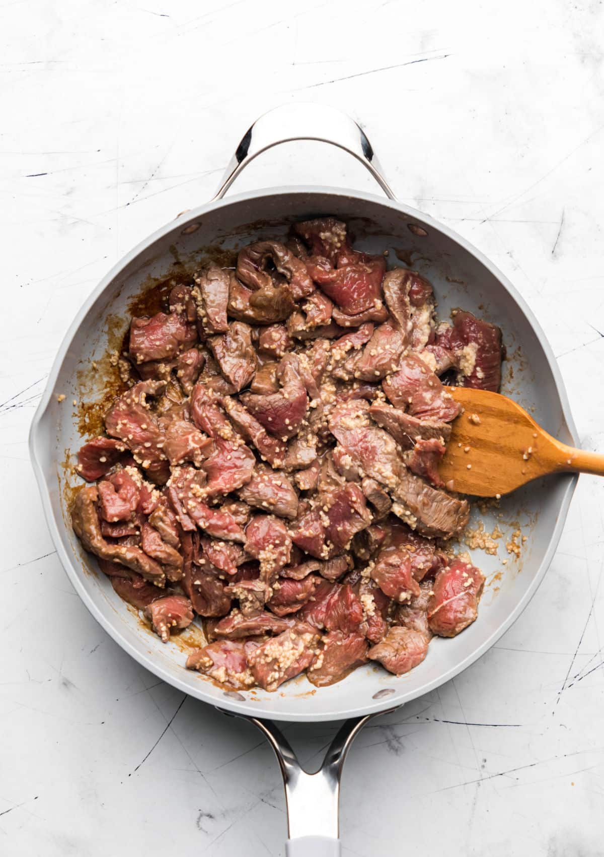 Sliced steak and garlic in a large skillet. 