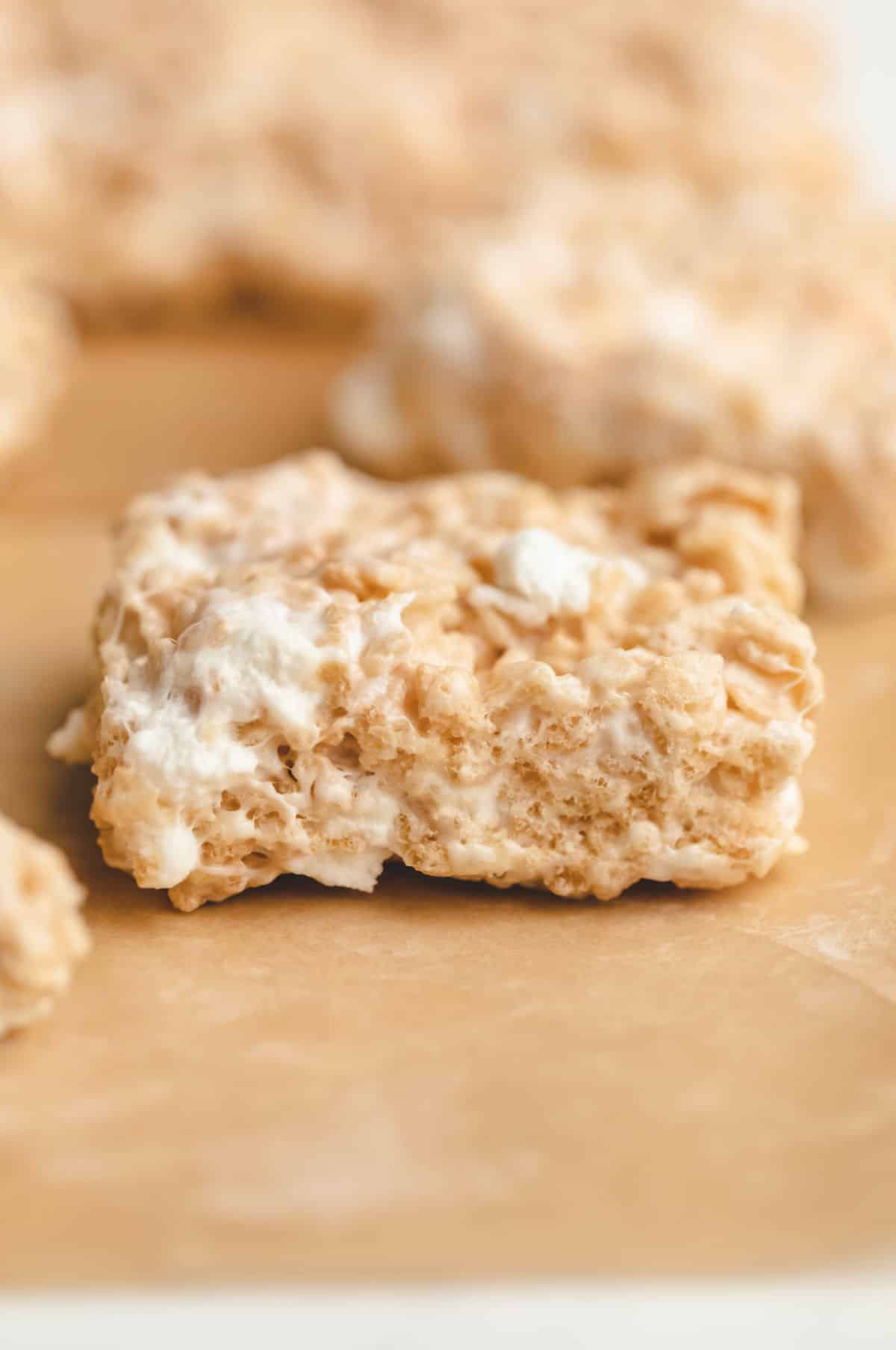 A single rice krispie treat on a piece of brown parchment paper. 
