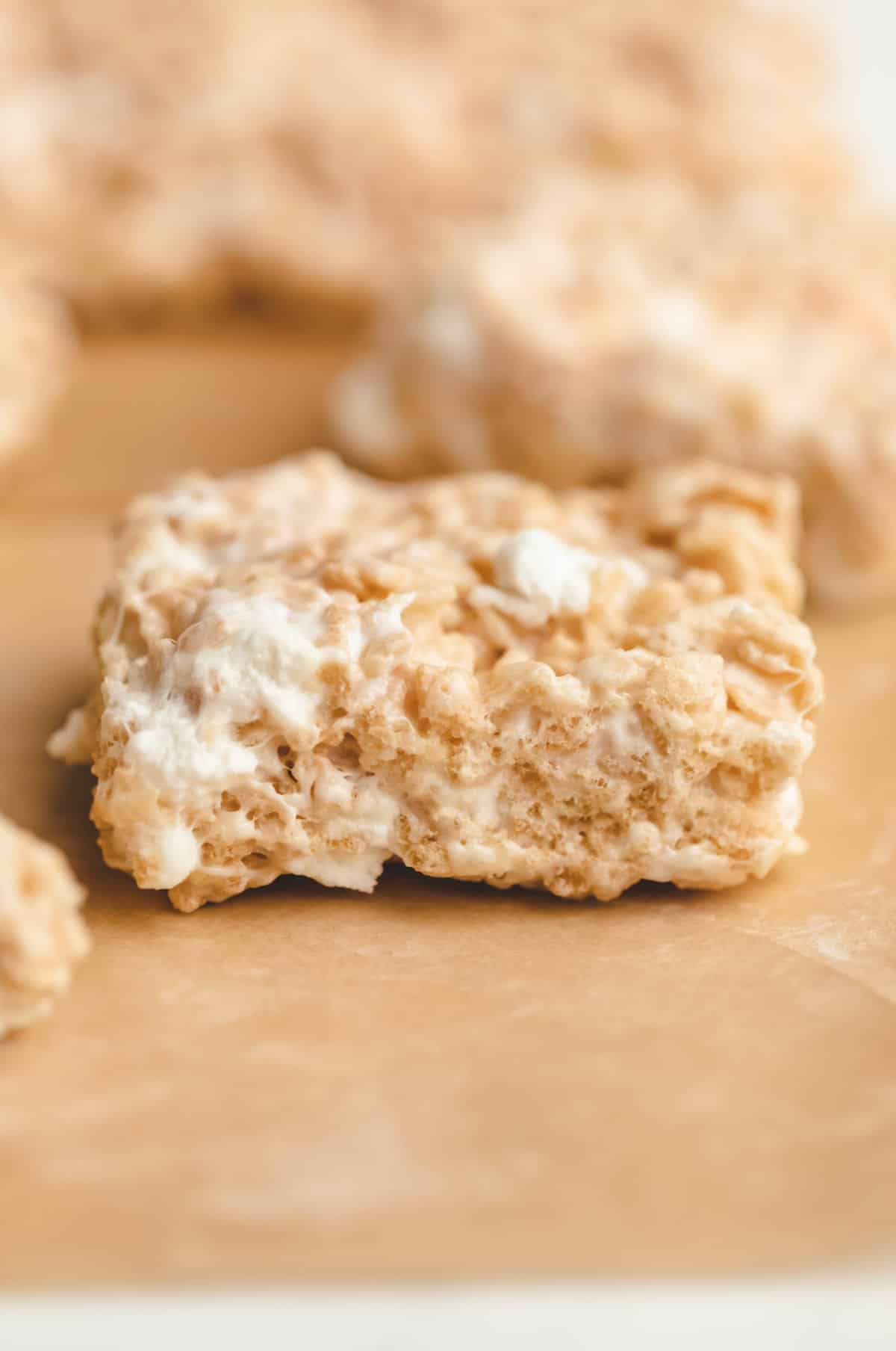 A single rice krispie treat on a piece of brown parchment paper.