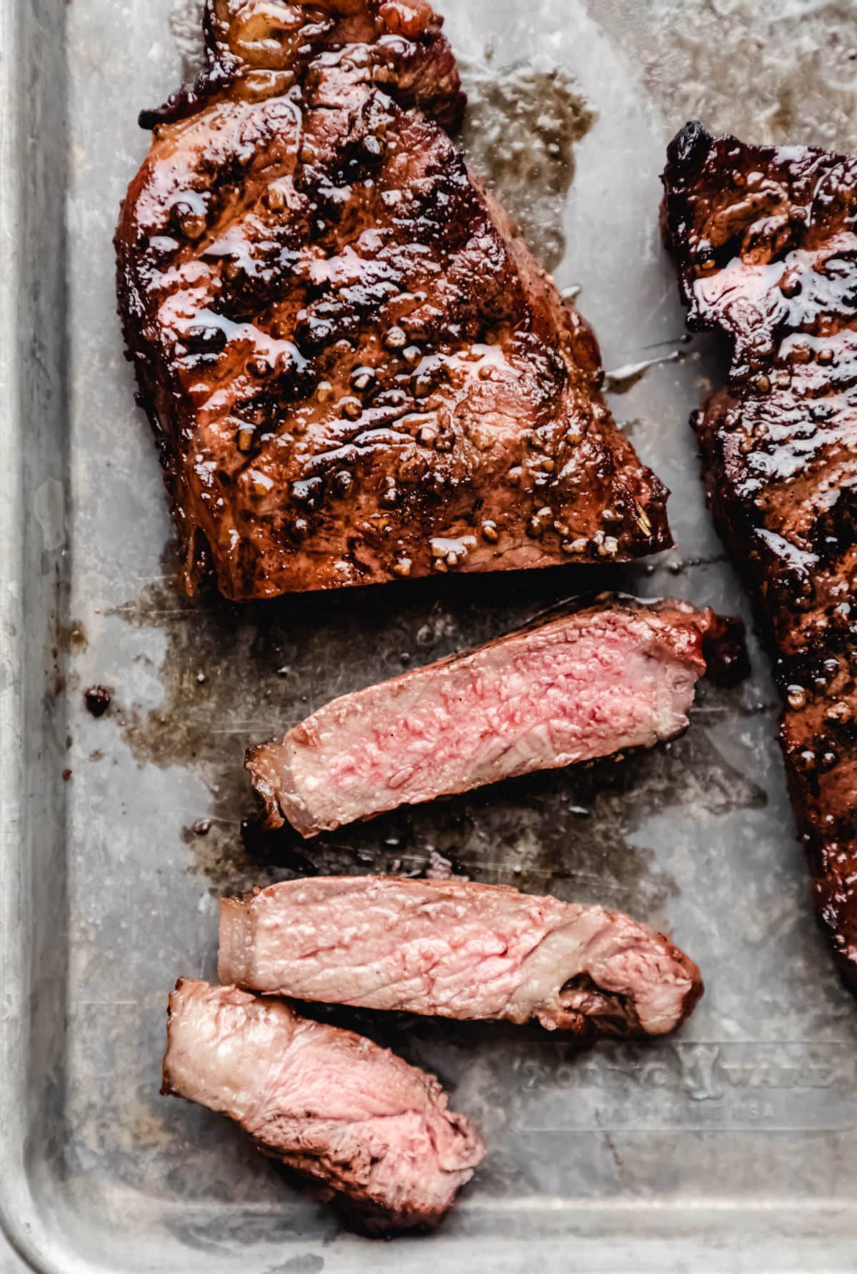 Grilled steak with three slices cut next to it. 