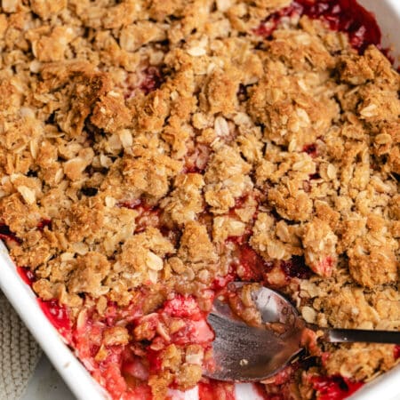 A silver spoon scooping out strawberry rhubarb crisp.