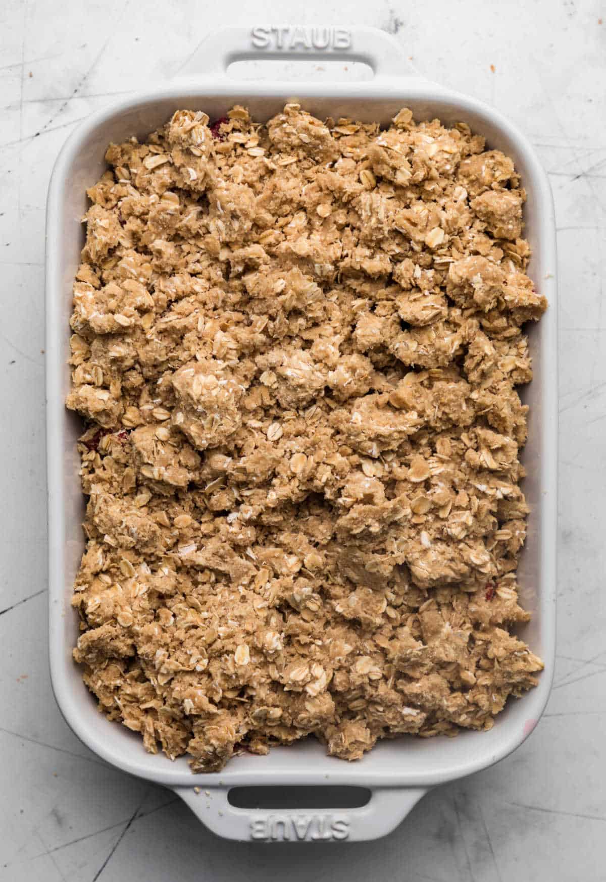 Unbaked strawberry rhubarb crisp in a white baking dish. 
