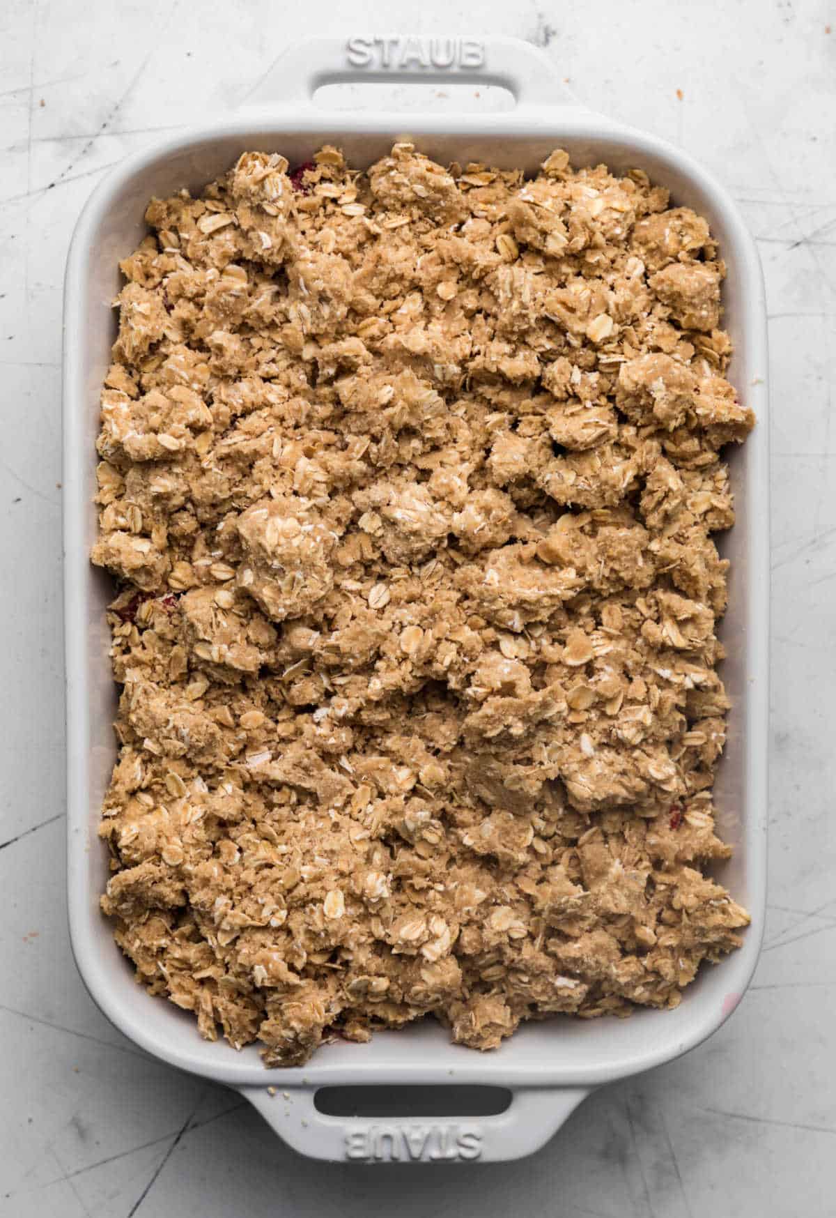 Unbaked strawberry rhubarb crisp in a white baking dish.