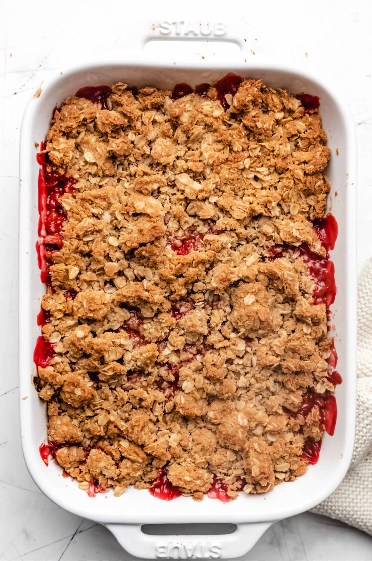 Baked strawberry rhubarb crisp in a white baking dish.