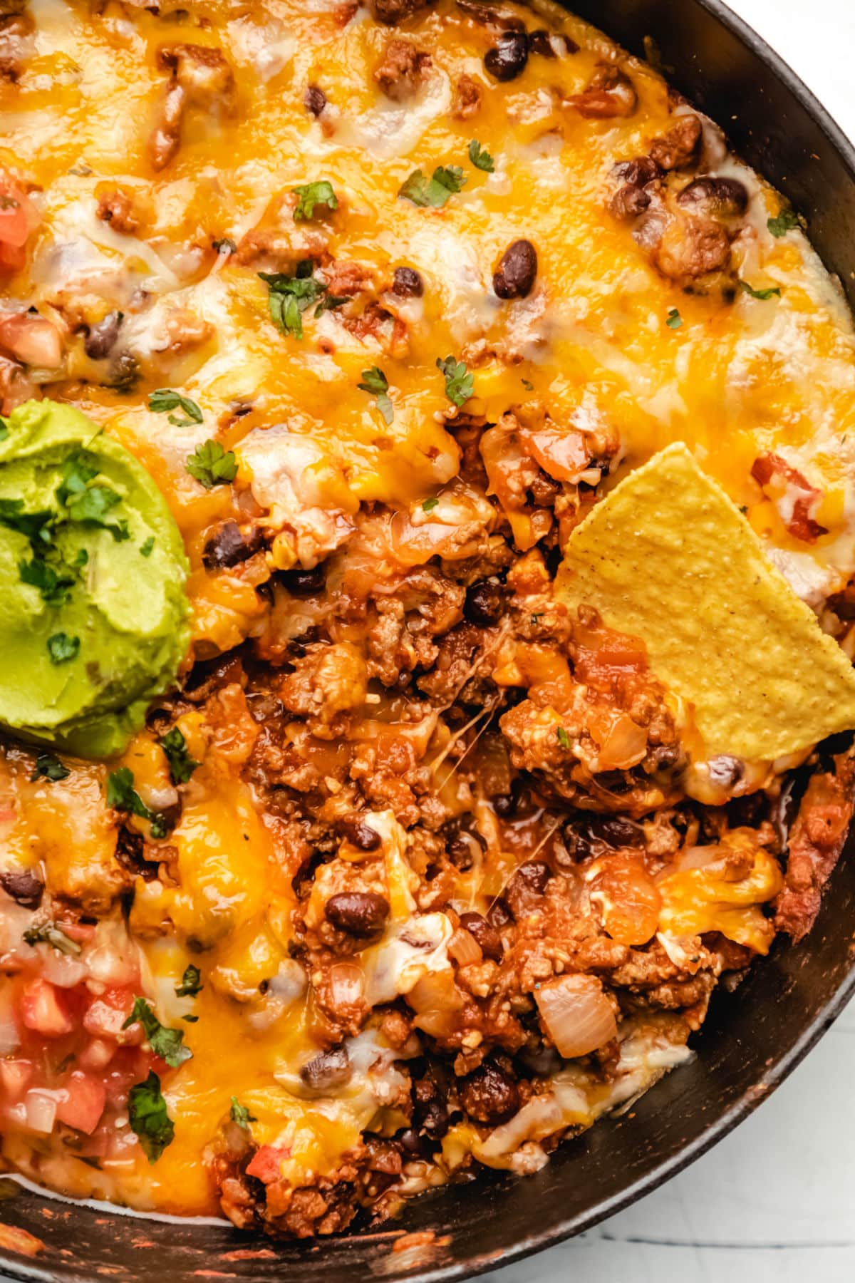 Taco casserole scooped onto a tortilla chip. 