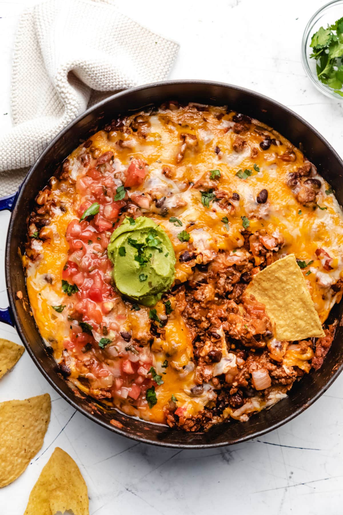 Taco casserole with a tortilla chip scooping up casserole. 