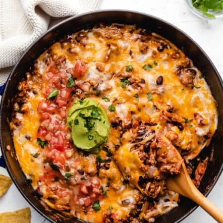 A wooden spoon scooping up taco casserole.