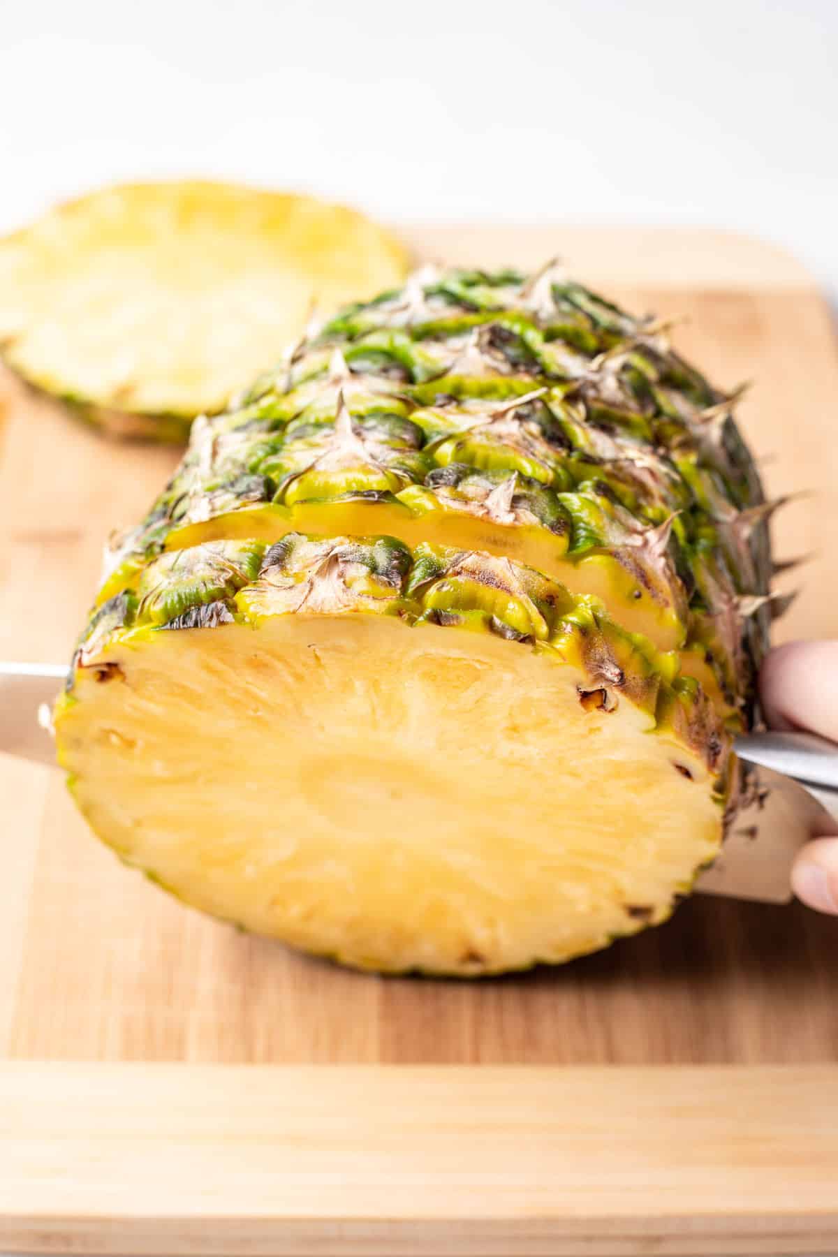 A knife cutting slices of pineapple. 