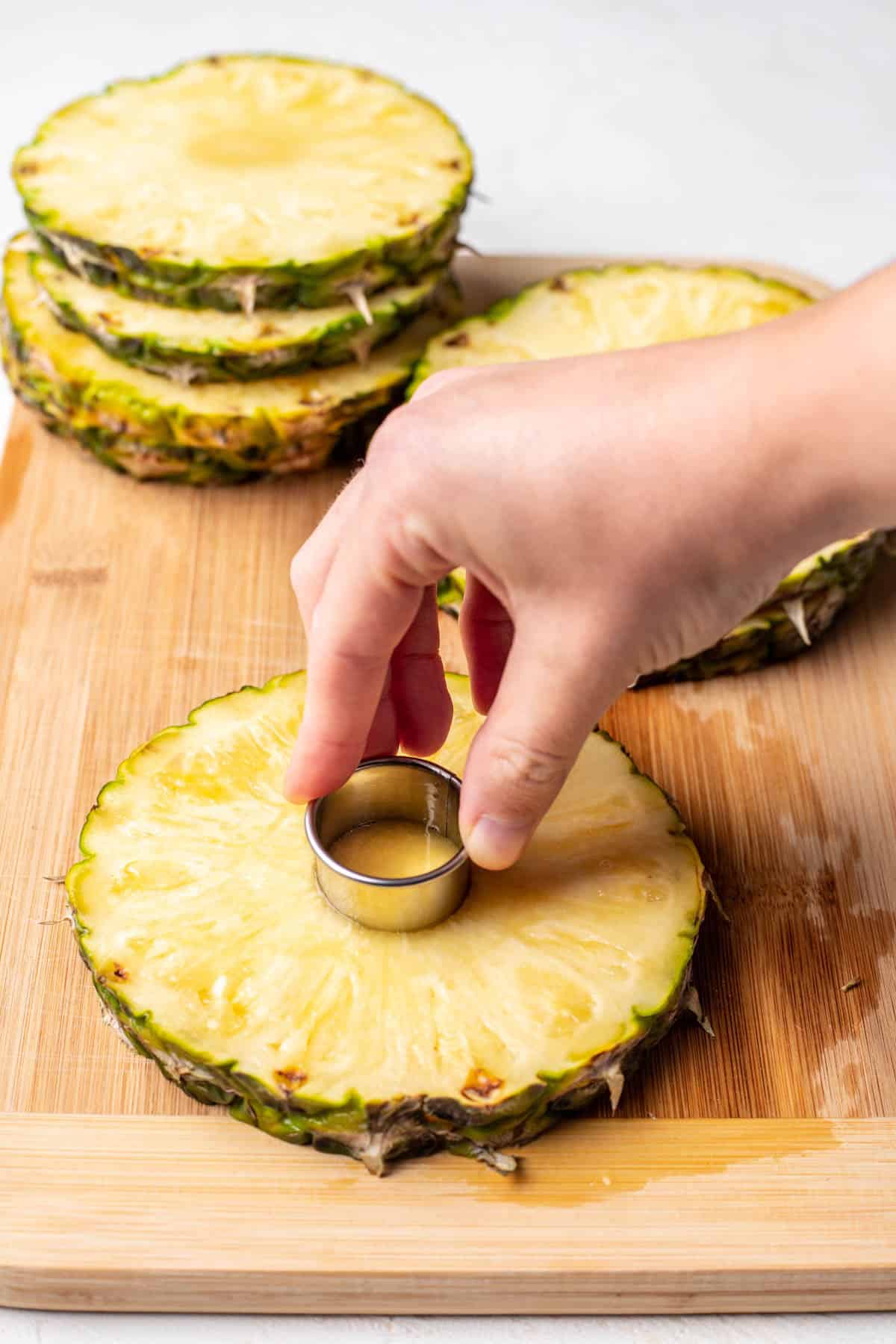 A corer cutting the core out of a pineapple slice. 