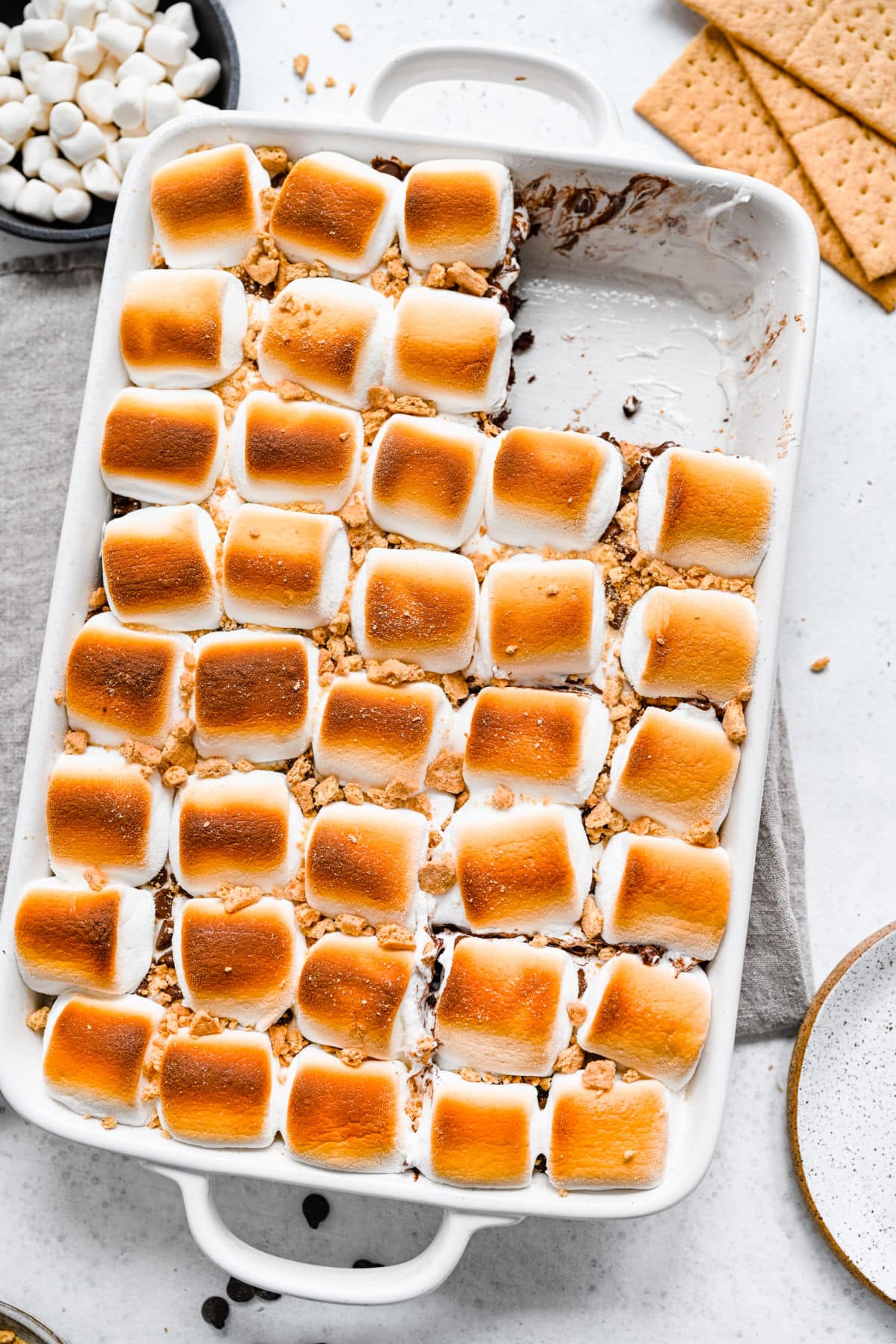 A pan of s'mores cake with a slice missing in the corner. 