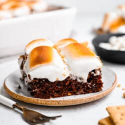 Slices of s'mores cake on plates next to a fork.