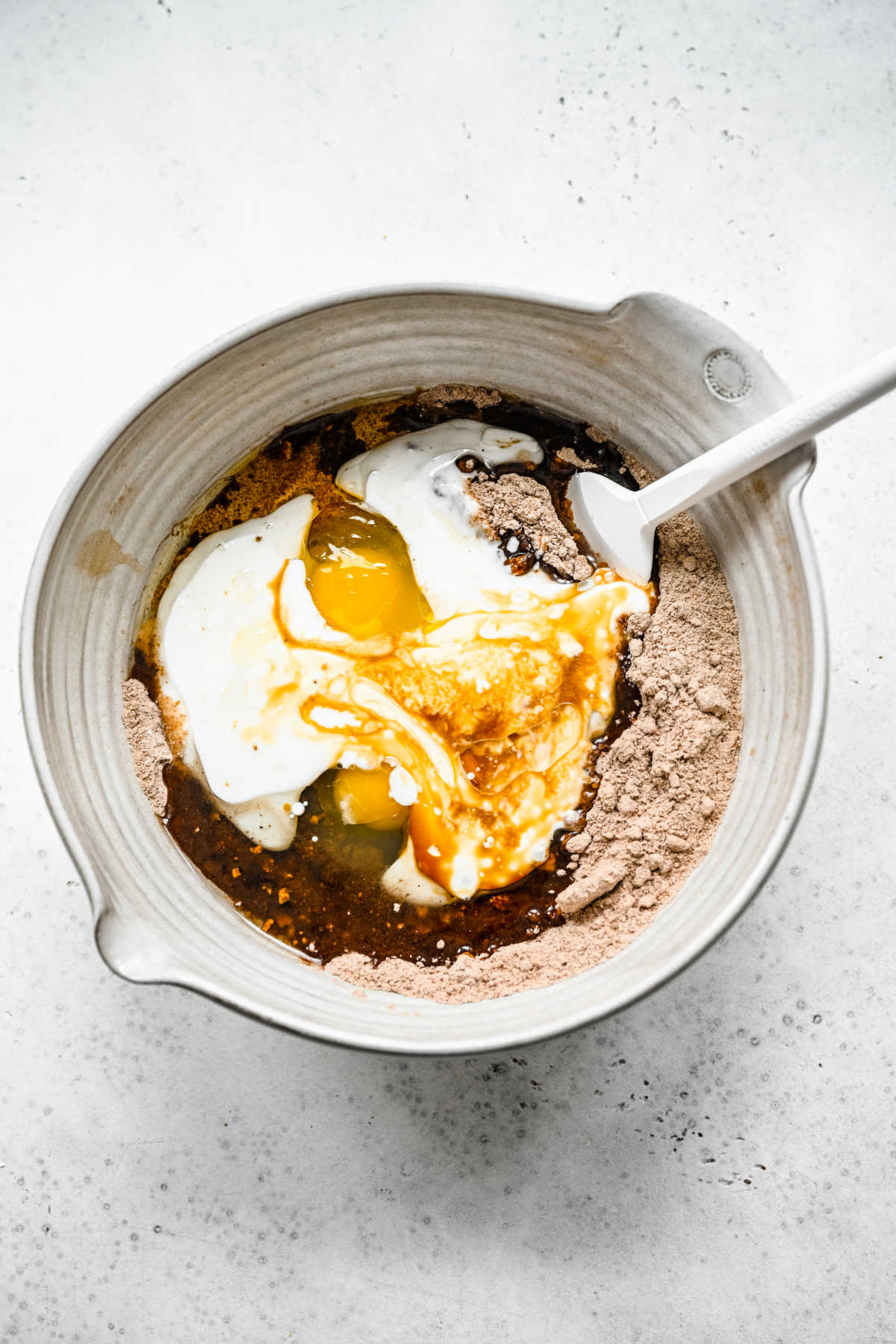 Wet ingredients on top of dry ingredients in a mixing bowl. 