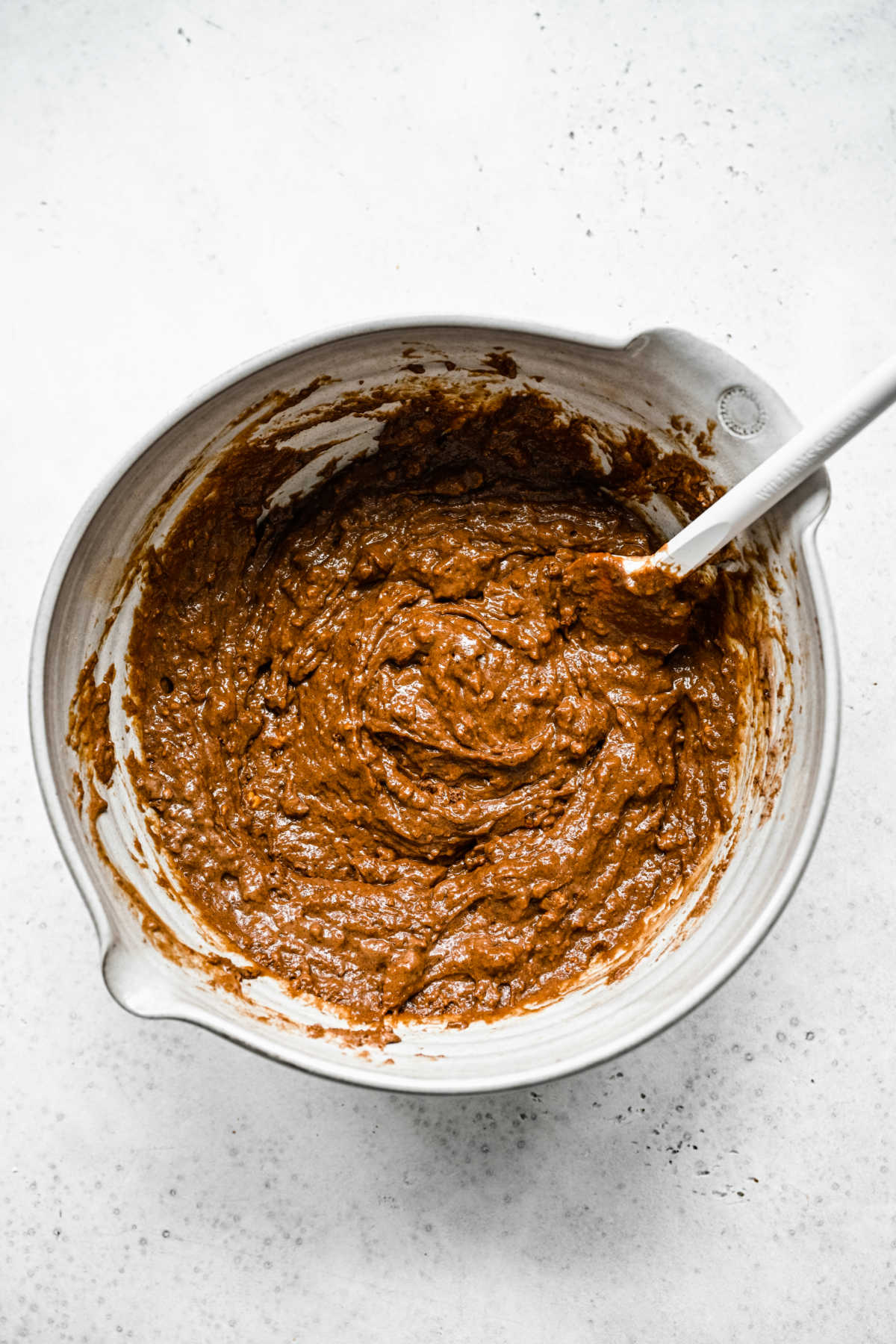 Chocolate cake batter with a white spoon in it. 