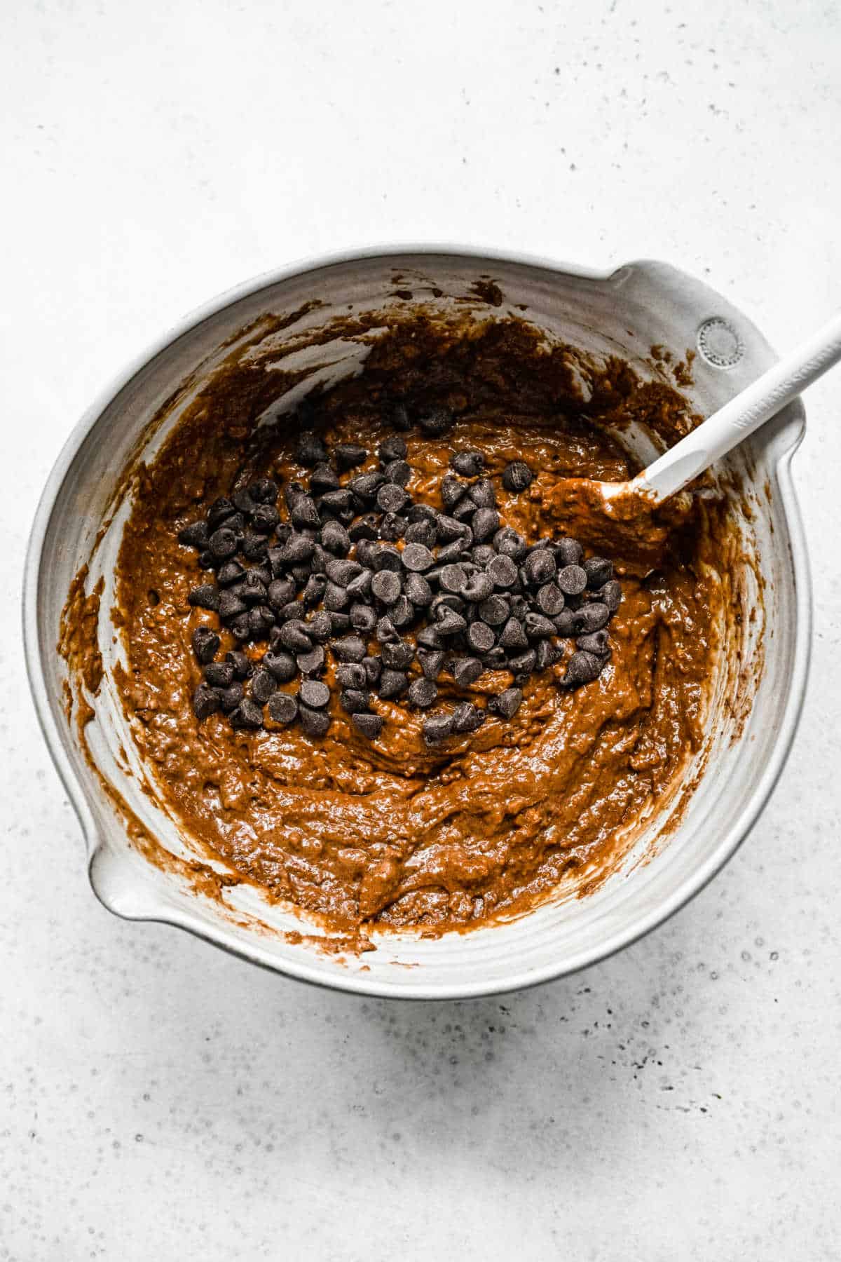 Chocolate chips on top of chocolate cake batter. 