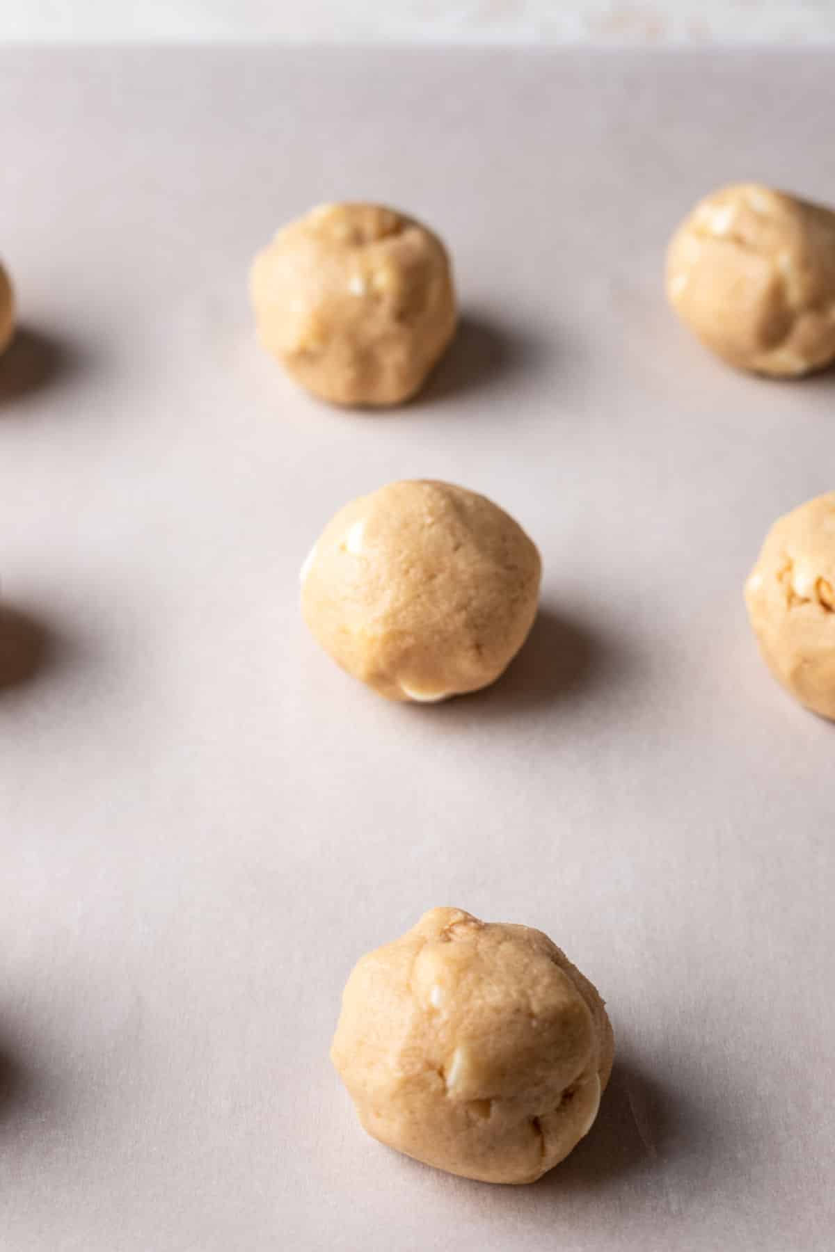 White chocolate macadamia nut cookie dough balls on a baking sheet. 