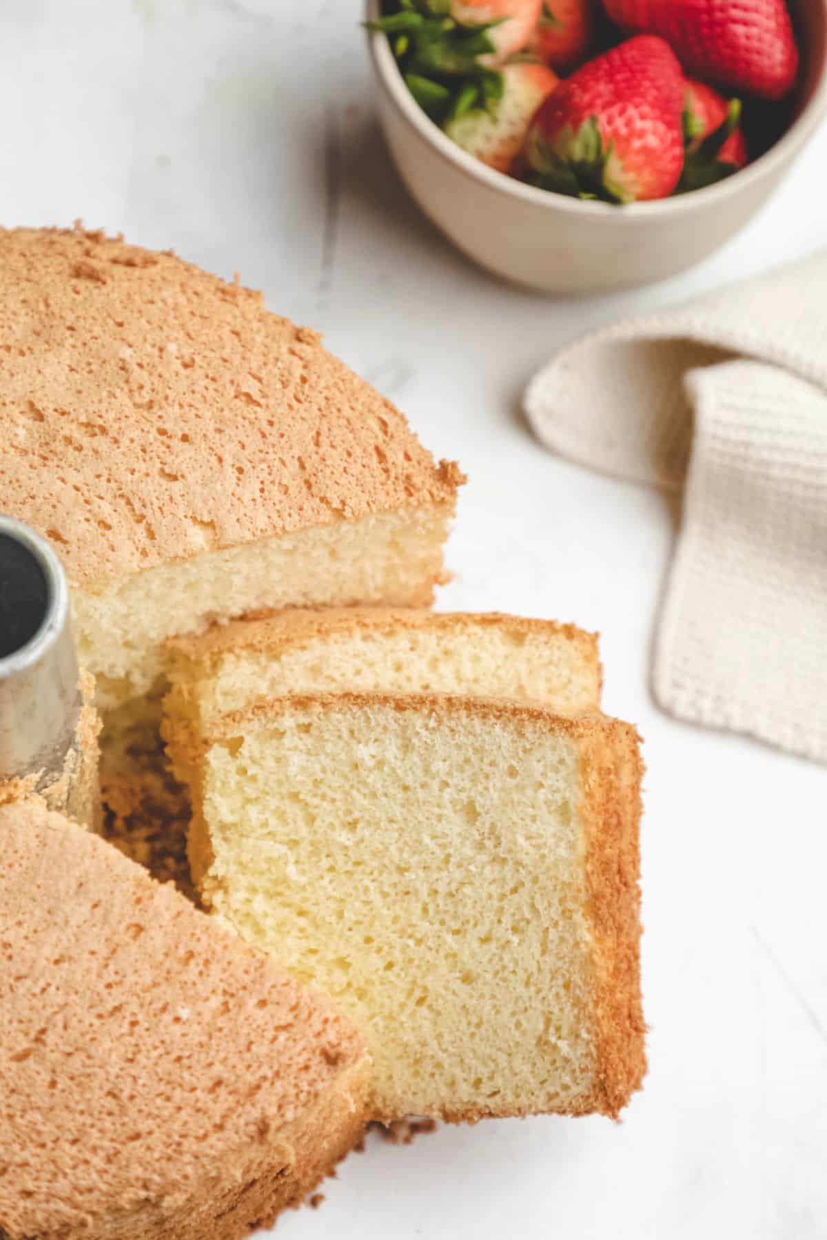 Two slices of chiffon cake next to the entire cake. 