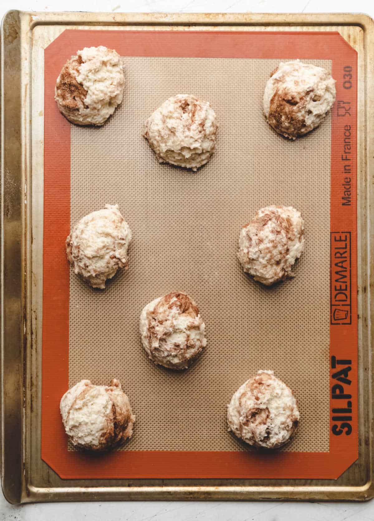 Unbaked cinnamon swirl biscuits on a baking sheet. 