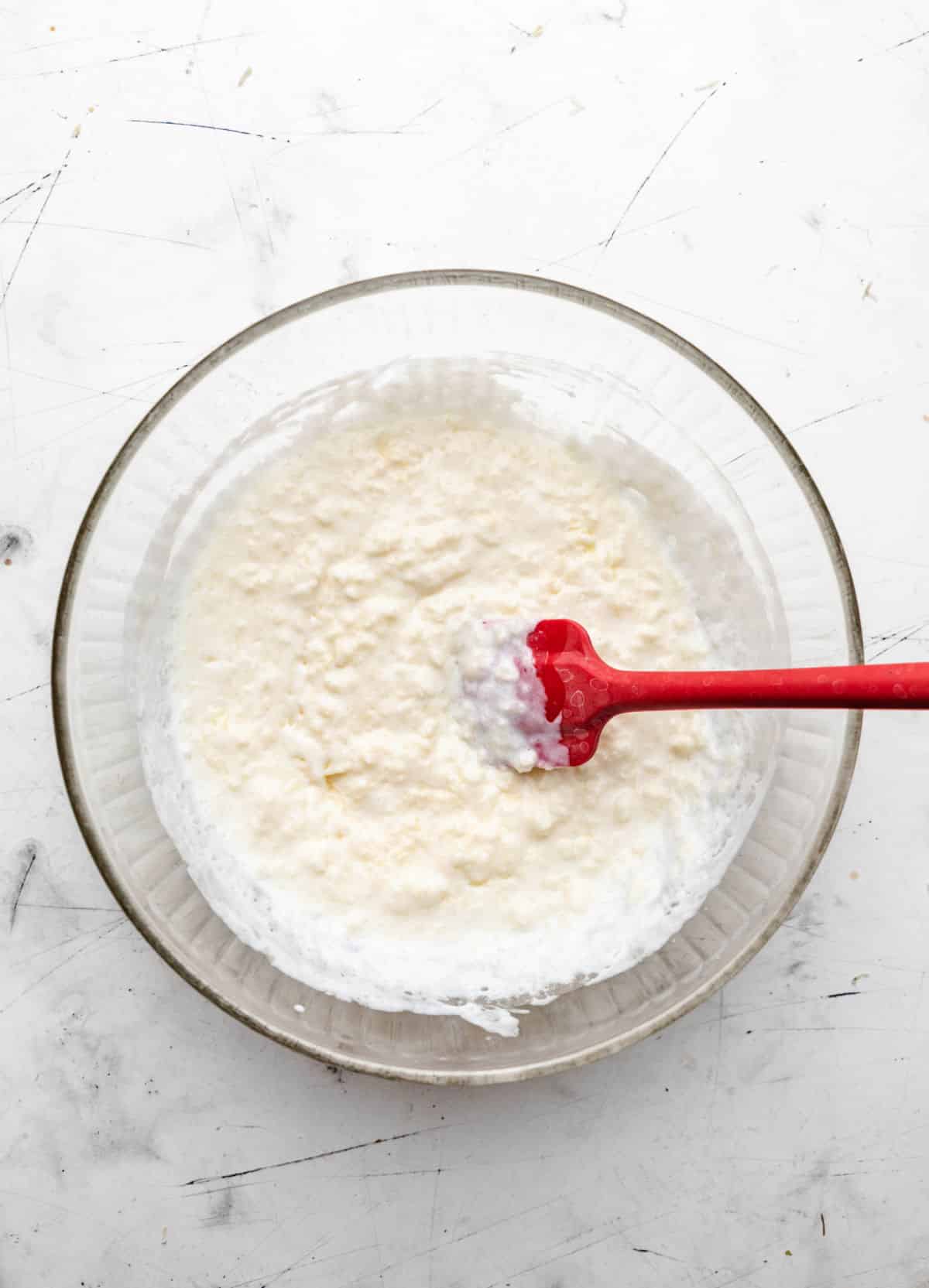 Clumpy butter in buttermilk in a mixing bowl. 