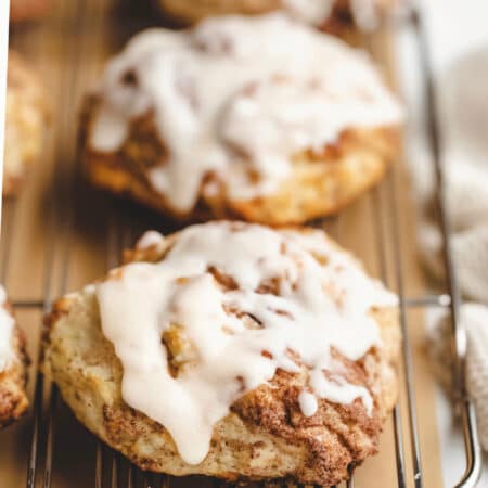 Iced cinnamon swirl biscuits on a wire cooling rack.