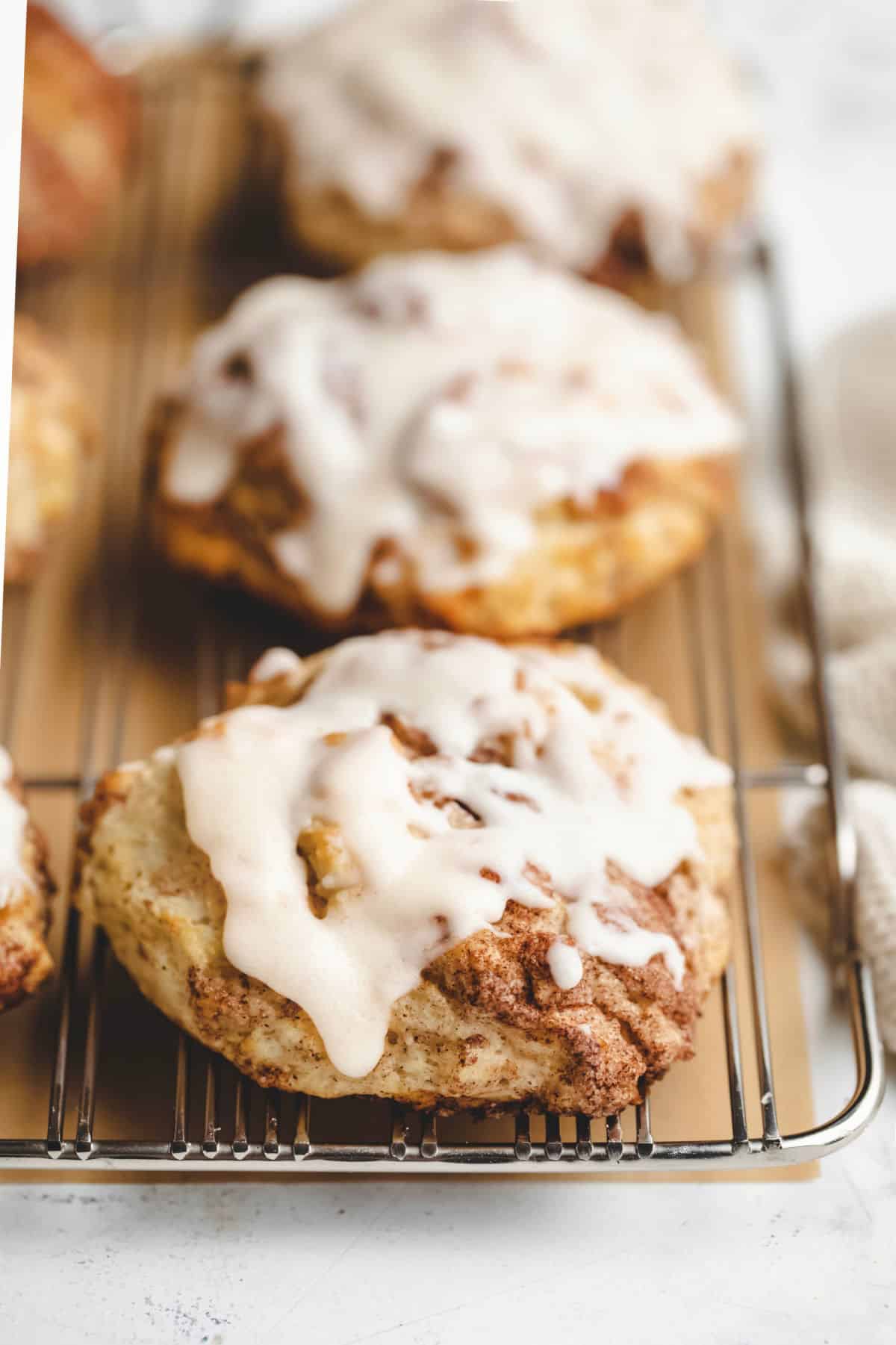 Iced cinnamon swirl biscuits on a wire cooling rack.