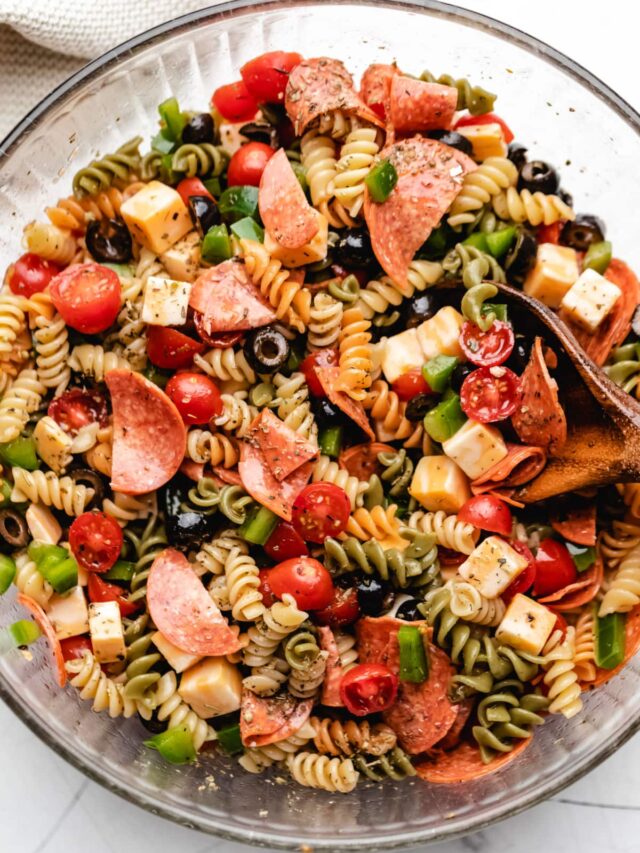 A glass mixing bowl full of pasta salad.
