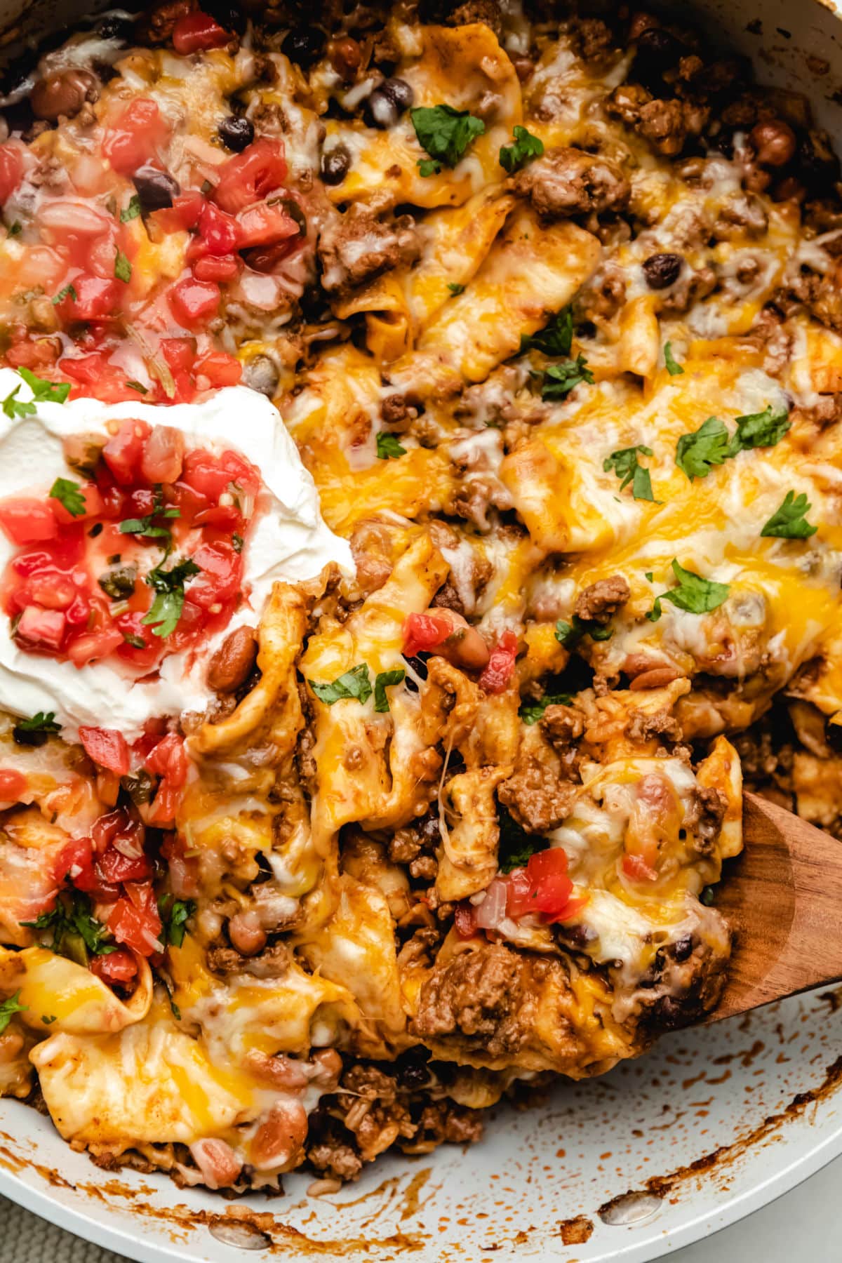 A wooden spoon scooping up ground beef burrito skillet. 